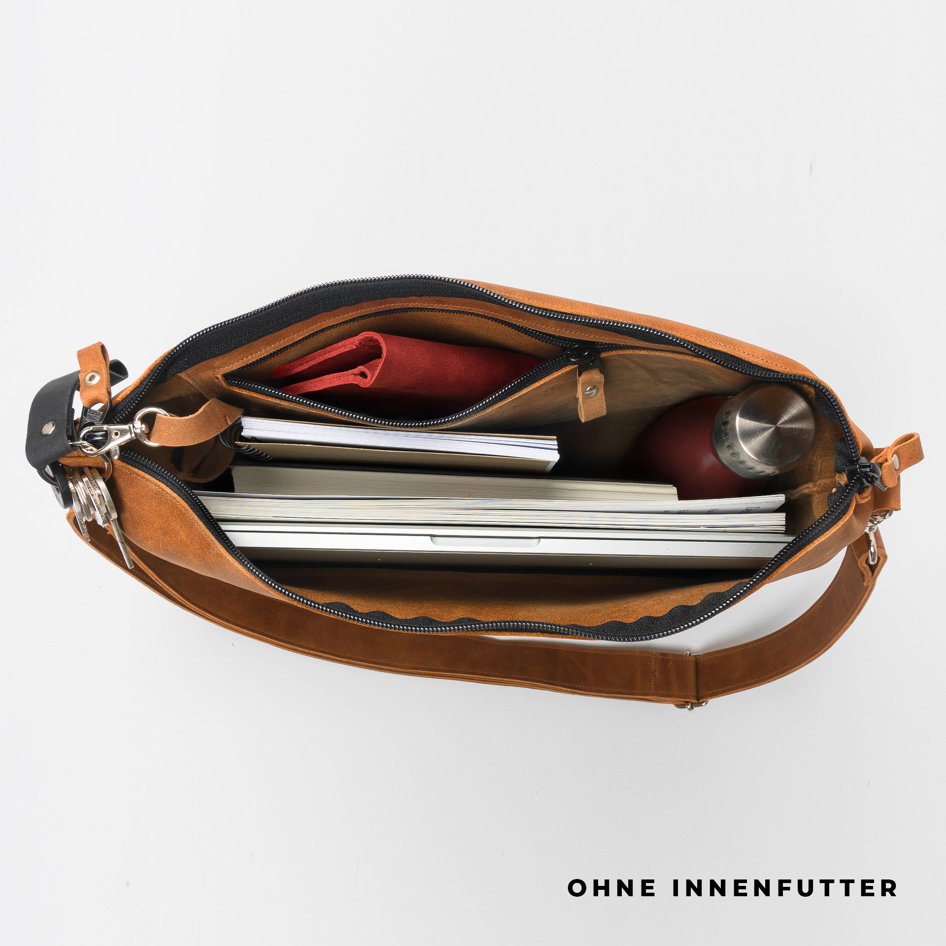 Ansicht von oben befüllte Umhängetasche ANA mit Schultergurt aus cognacfarbenem geöltem Naturleder