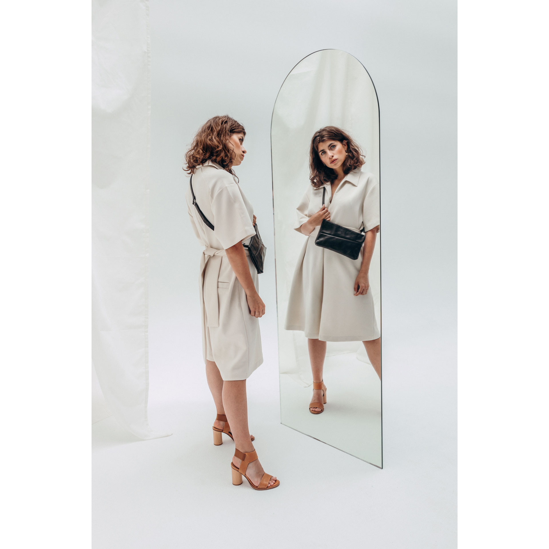 Model schaut sich im Spiegel die 3-in-1 Tasche Isa in schwarz geöltem Naturleder an