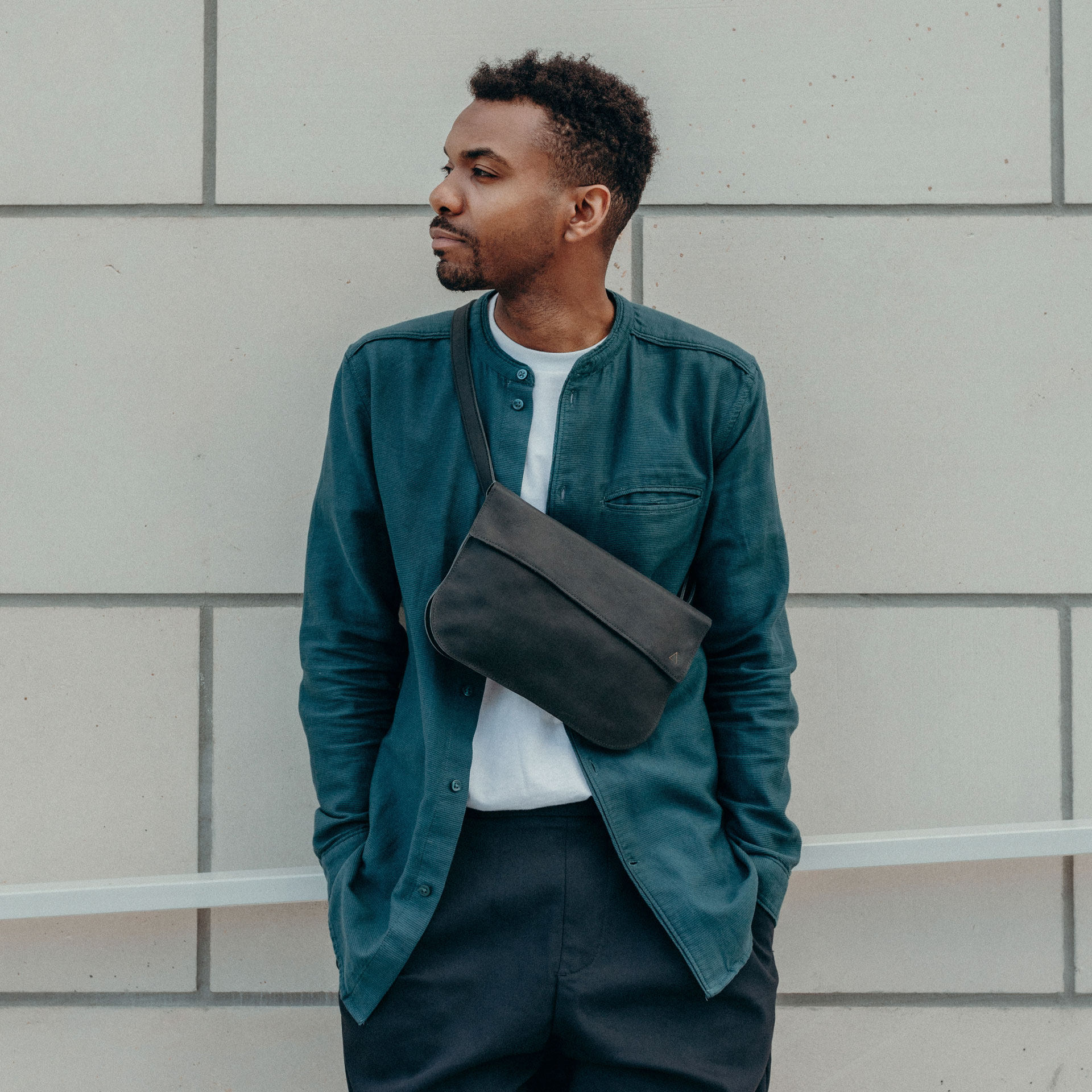 Männliches Model trägt Crossbody Bag TEA Large in der Farbe Kohle.