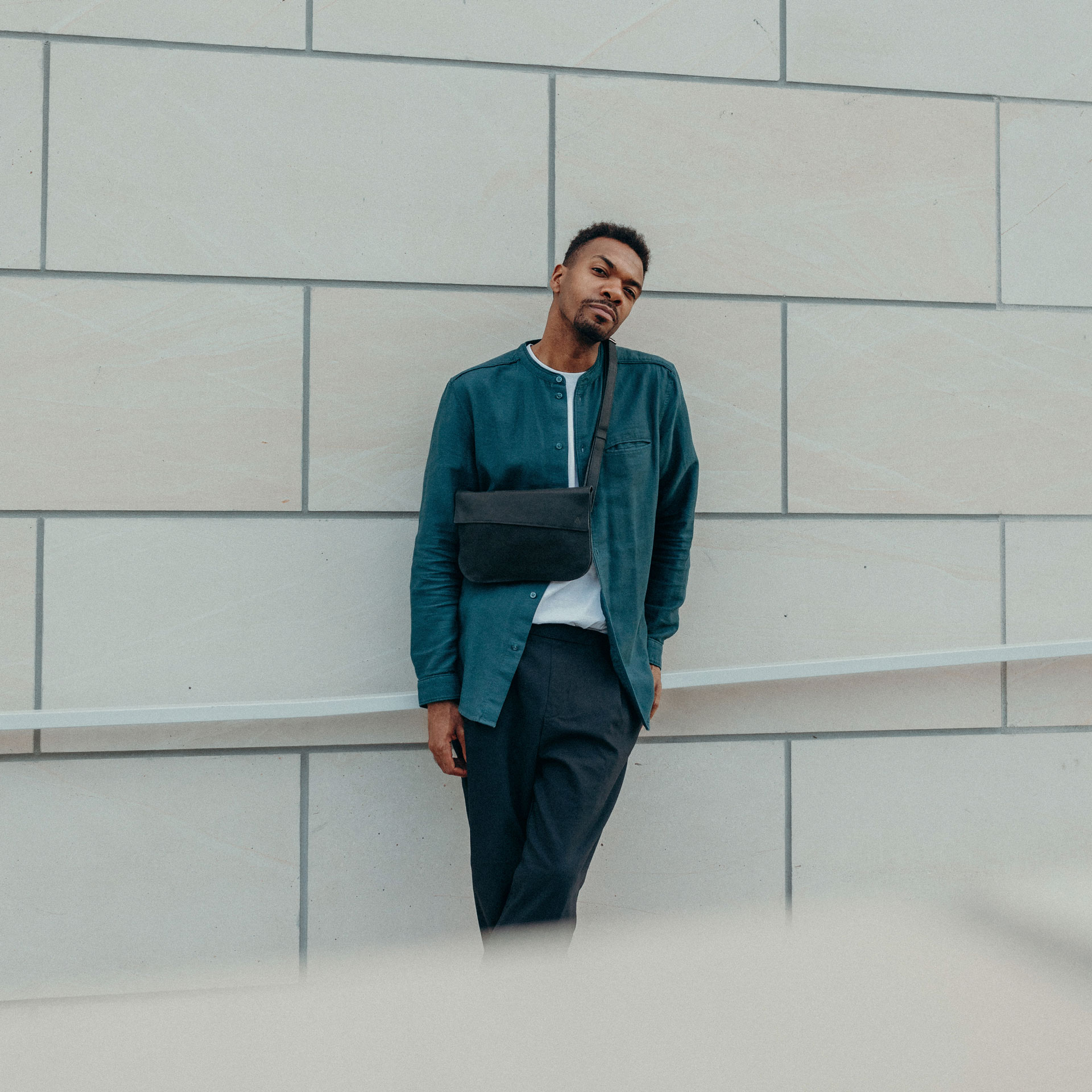 Männliches Model trägt Crossbody Bag TEA Large in der Farbe Kohle.