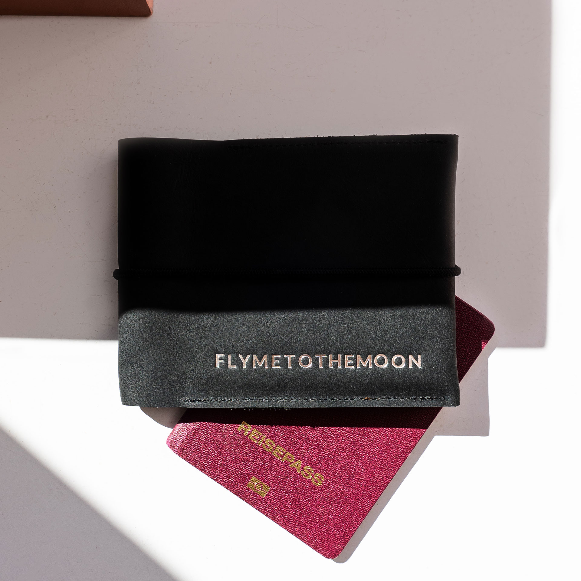 Mood Shot Familienreisepasshülle EVE aus nachhaltigem Naturleder in Kohle mit schwarzem Verschlussband und individueller Prägung in Silber