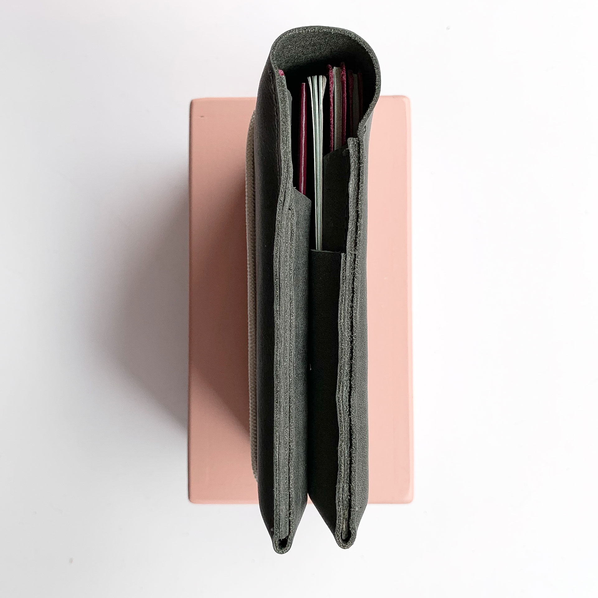 Draufsicht auf Familienreisepasshülle EVE aus nachhaltigem Naturleder in Steingrau mit cremefarbenem Verschlussband und vier Reisepässen