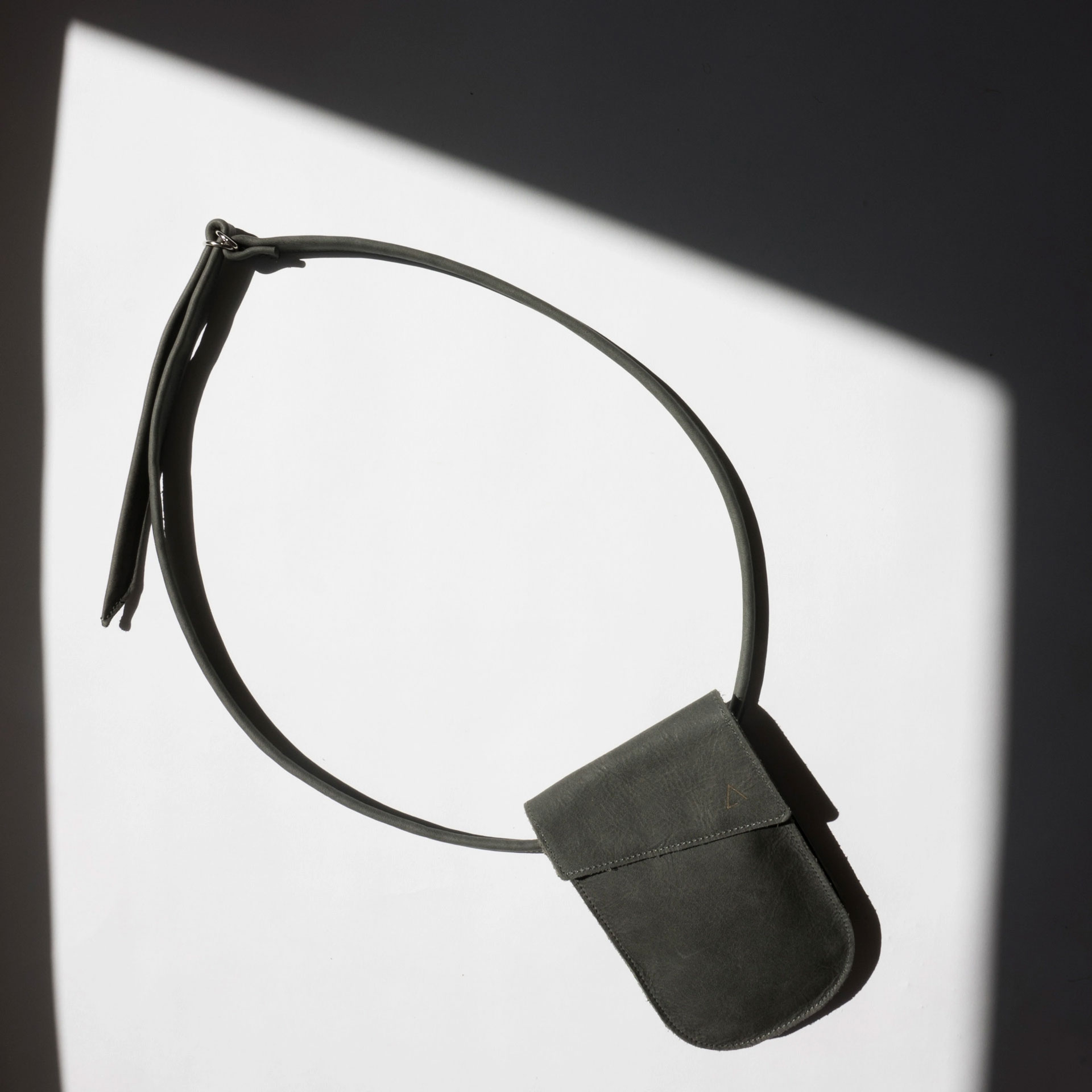 Mood Shot Handytasche Brustbeutel IRA aus nachhaltigem Naturleder in Kohle mit langem Träger in Sonne liegend