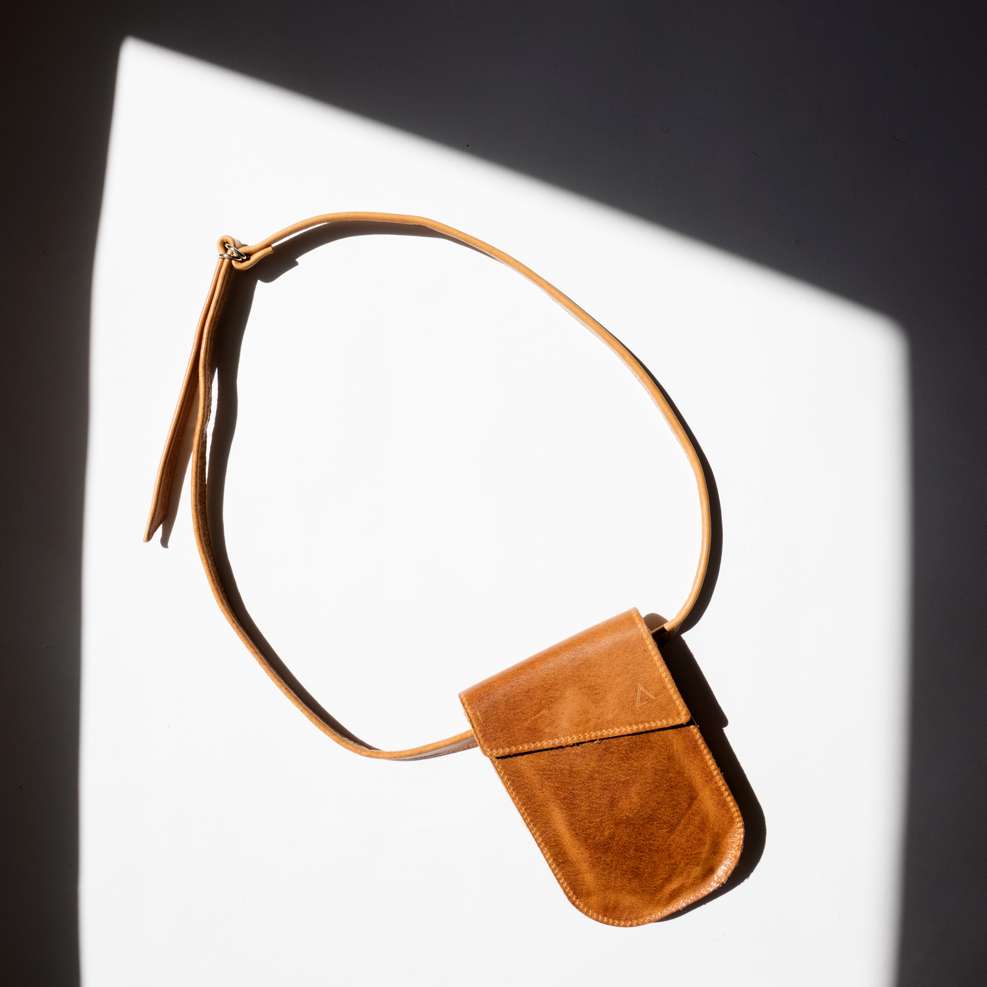 Mood Shot Handytasche Brustbeutel IRA aus nachhaltigem Naturleder in Cognac geölt mit langem Träger in Sonne liegend