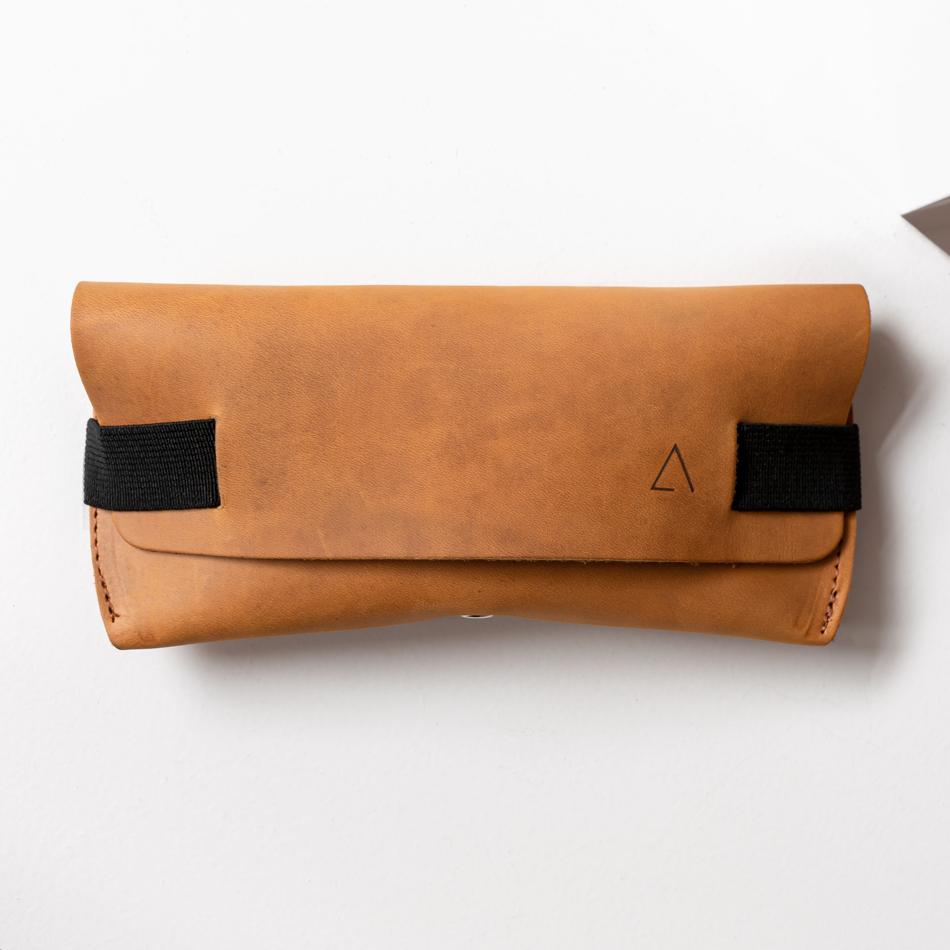 Brillenetui LUK in Cognac geölt mit schwarzem Verschlussband von vorn mit Logoprägung