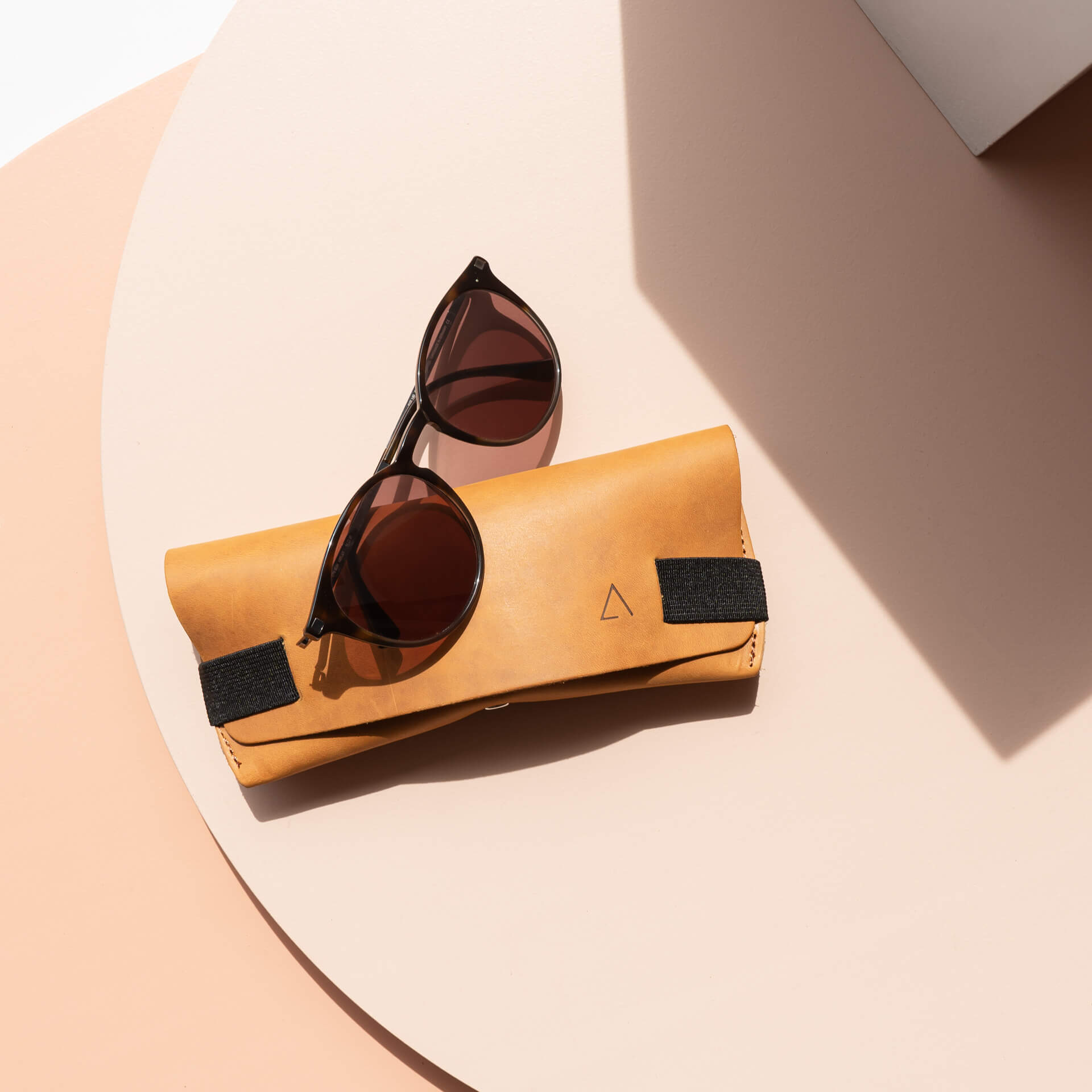 Brillenetui LUK aus nachhaltigem Naturleder in Cognac mit schwarzem Verschlussband von vorn mit Sonnenbrille