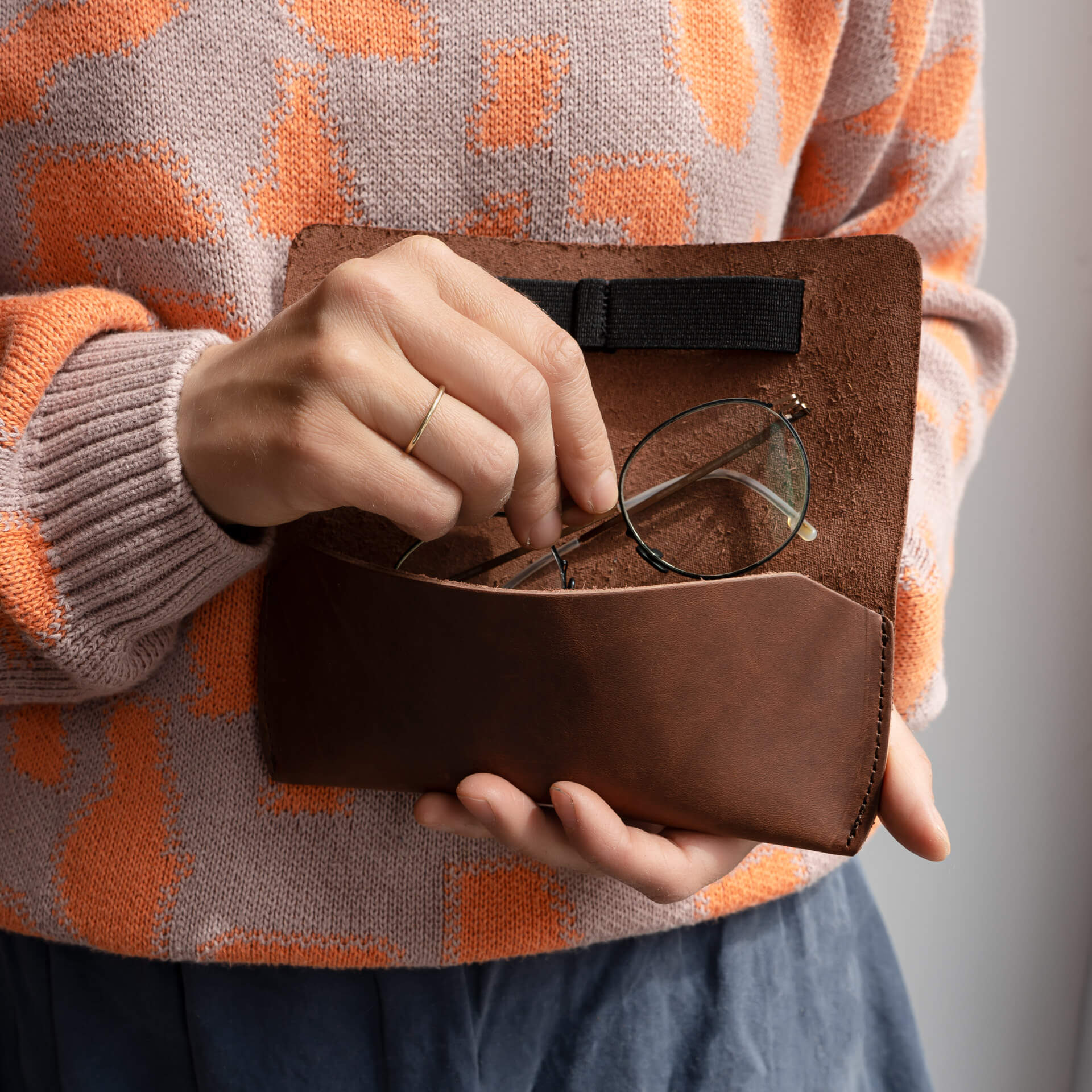 Frau legt Brille in Brillenetui LUK aus nachhaltigem Naturleder in Dunkelbrau