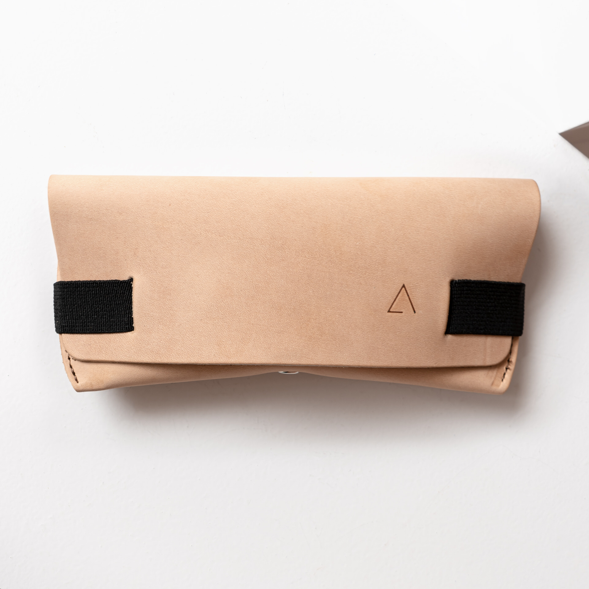 Brillenetui LUK in Hellbraun mit schwarzem Verschlussband Vorderseite mit Logoprägung