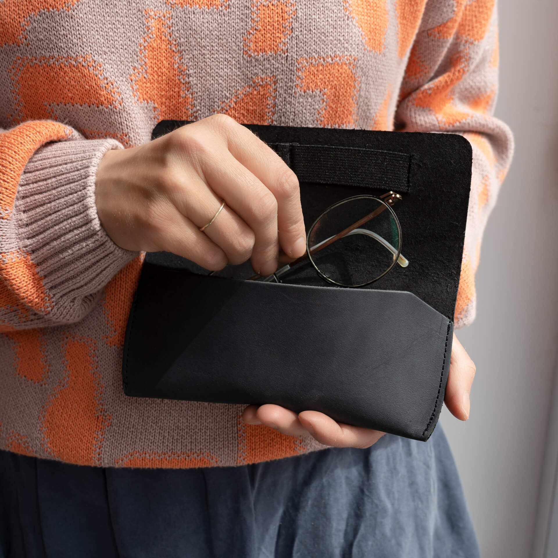 Frau legt Brille in Brillenetui LUK aus nachhaltigem Naturleder in Kohle