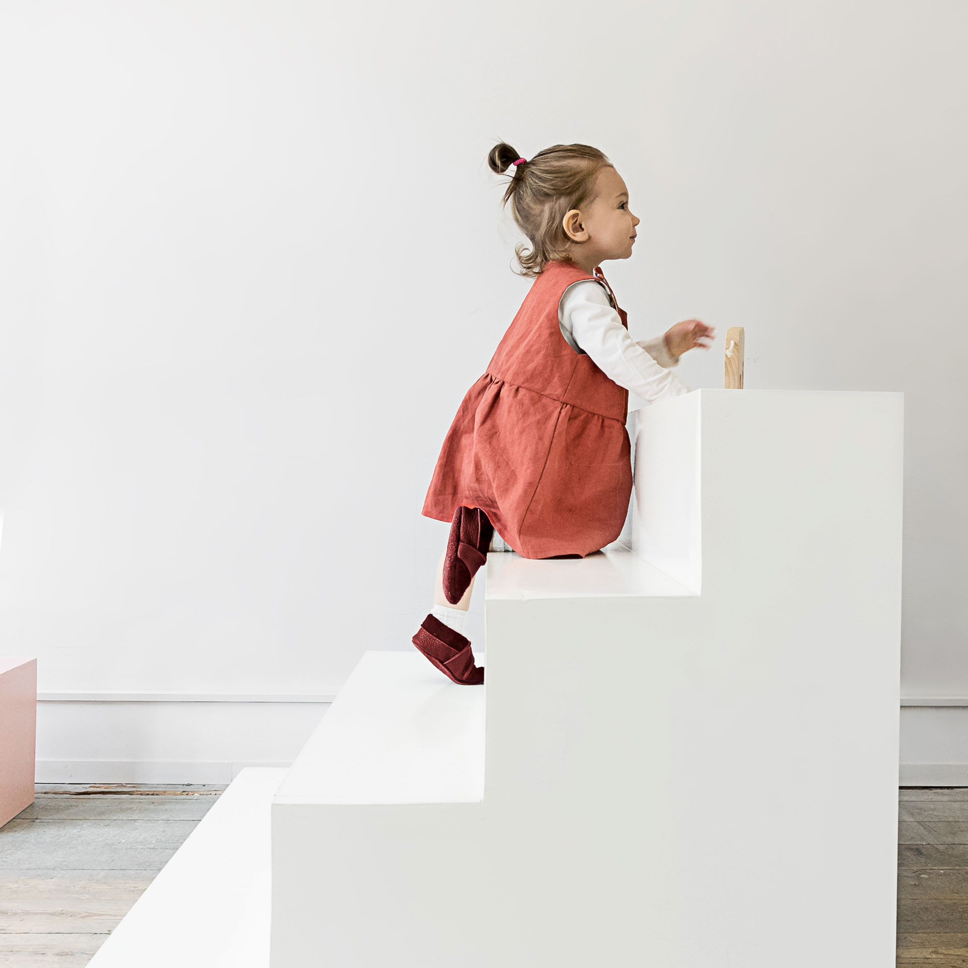 Kind krabbelt Treppe mit den Lauflernschuhen MOQ in der Farbe Weinrot hinauf.
