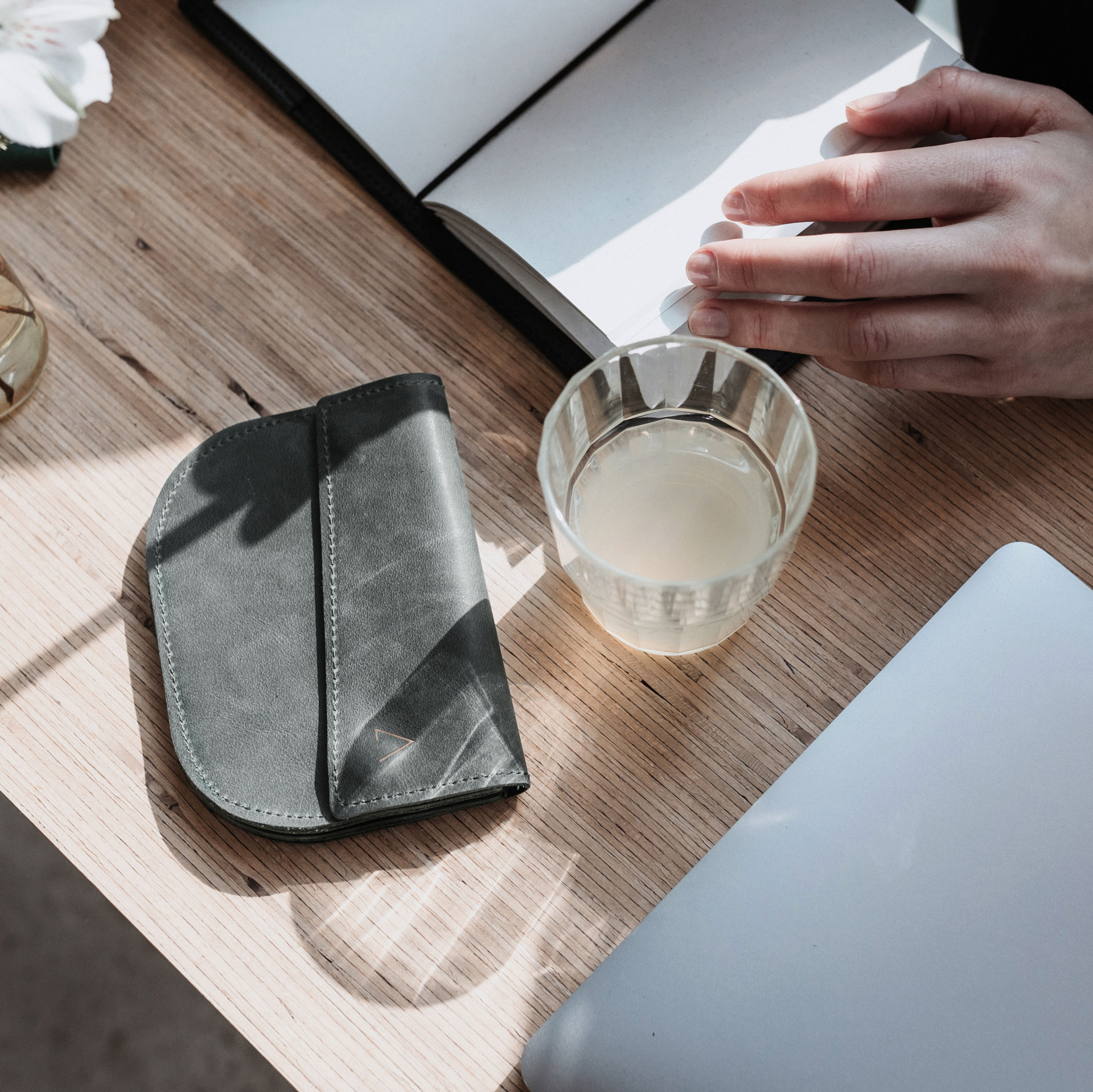 Kleines Portemonnaie UNA in Steingrau im Größenvergleich mit Notizbuch und Wasserglas
