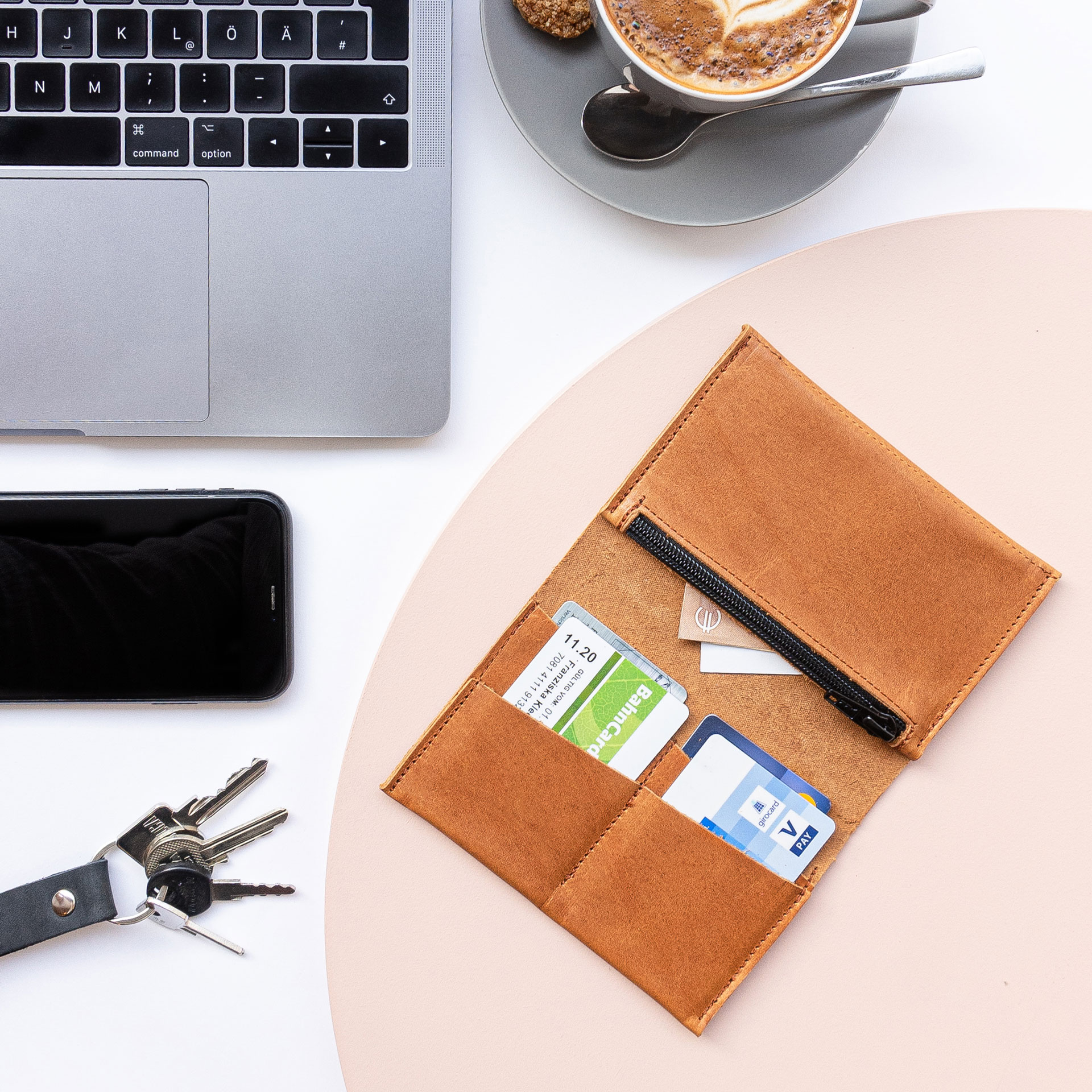 Brieftasche OLI Large von innen mit Karten und Geldscheinen im Größenvergleich mit Laptop, Kaffeetasse, Handy und Schlüsselbund