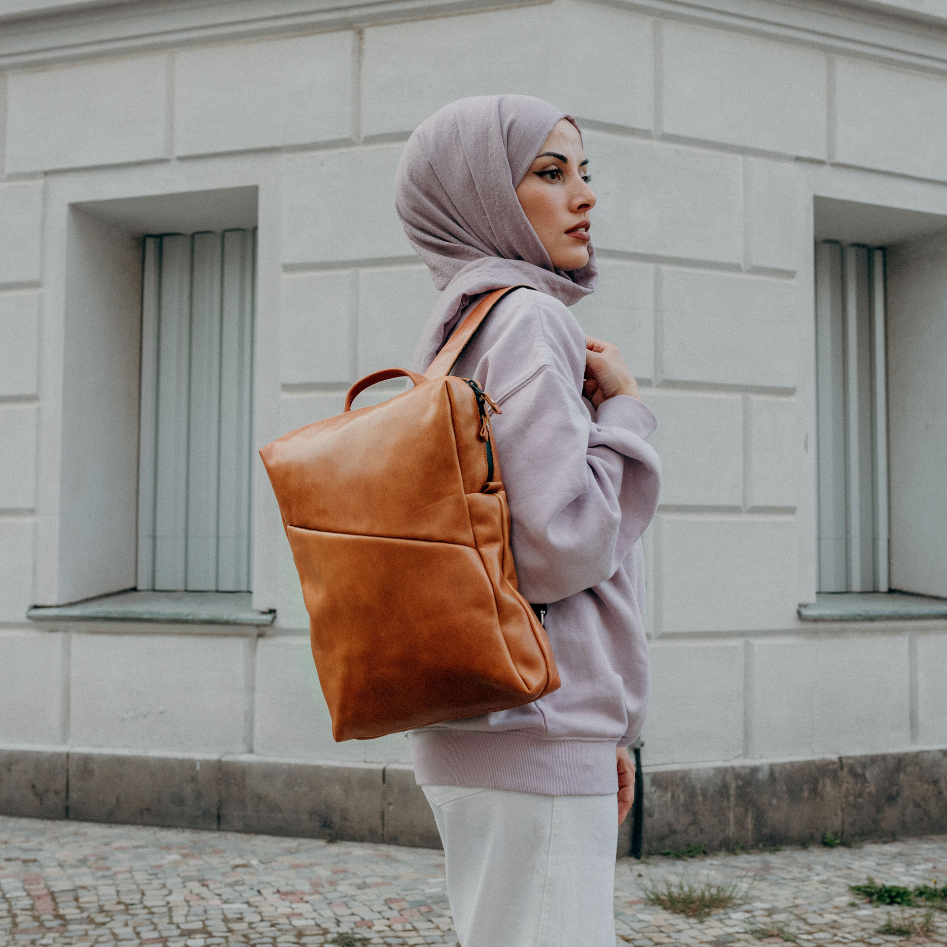 Model trägt Rucksack Neo Large in cognac geölt aus nachhaltigem Naturleder auf dem Rücken.