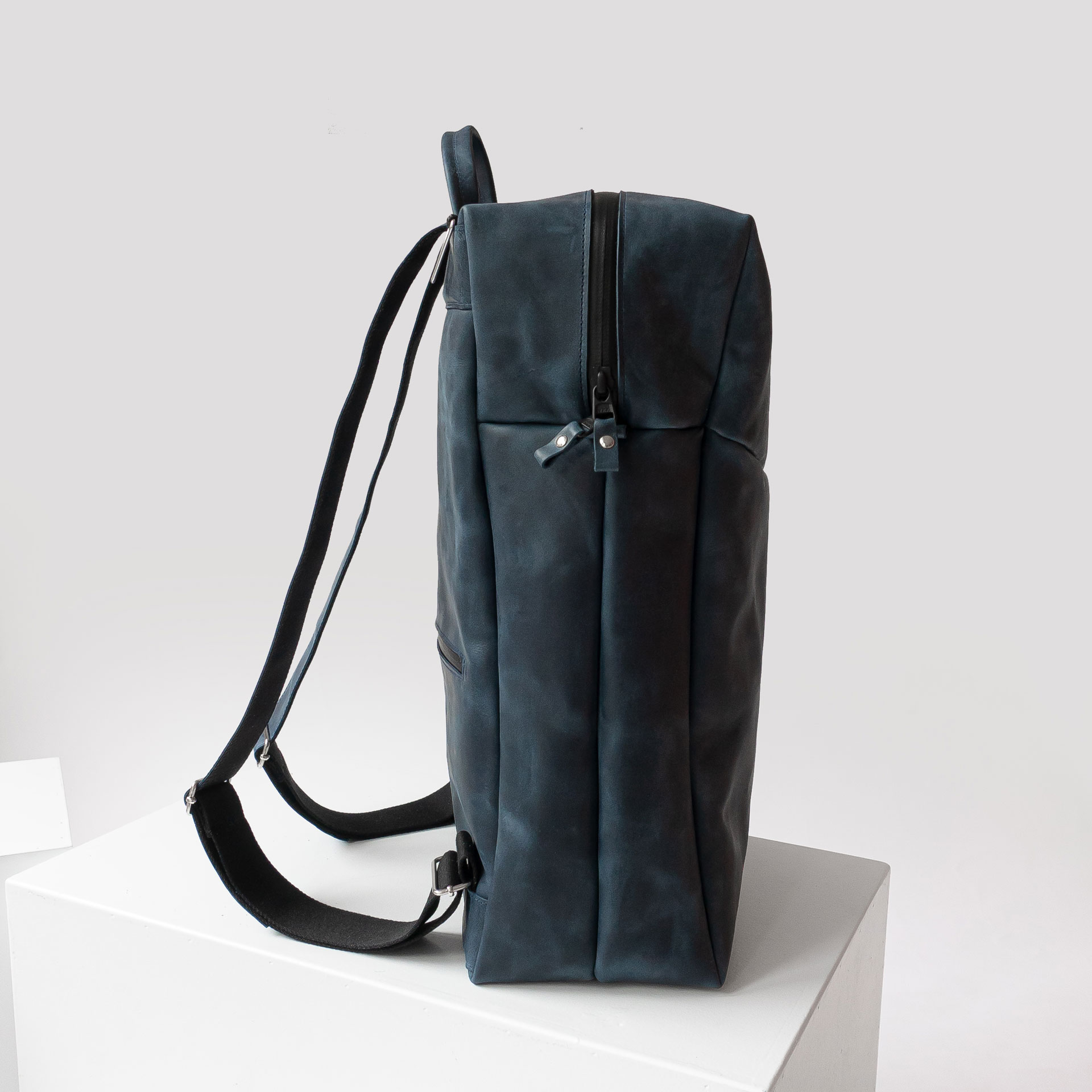 Seitenansicht des Rucksacks NEO LARGE aus Naturleder in Dunkelblau mit Wickelfunktion