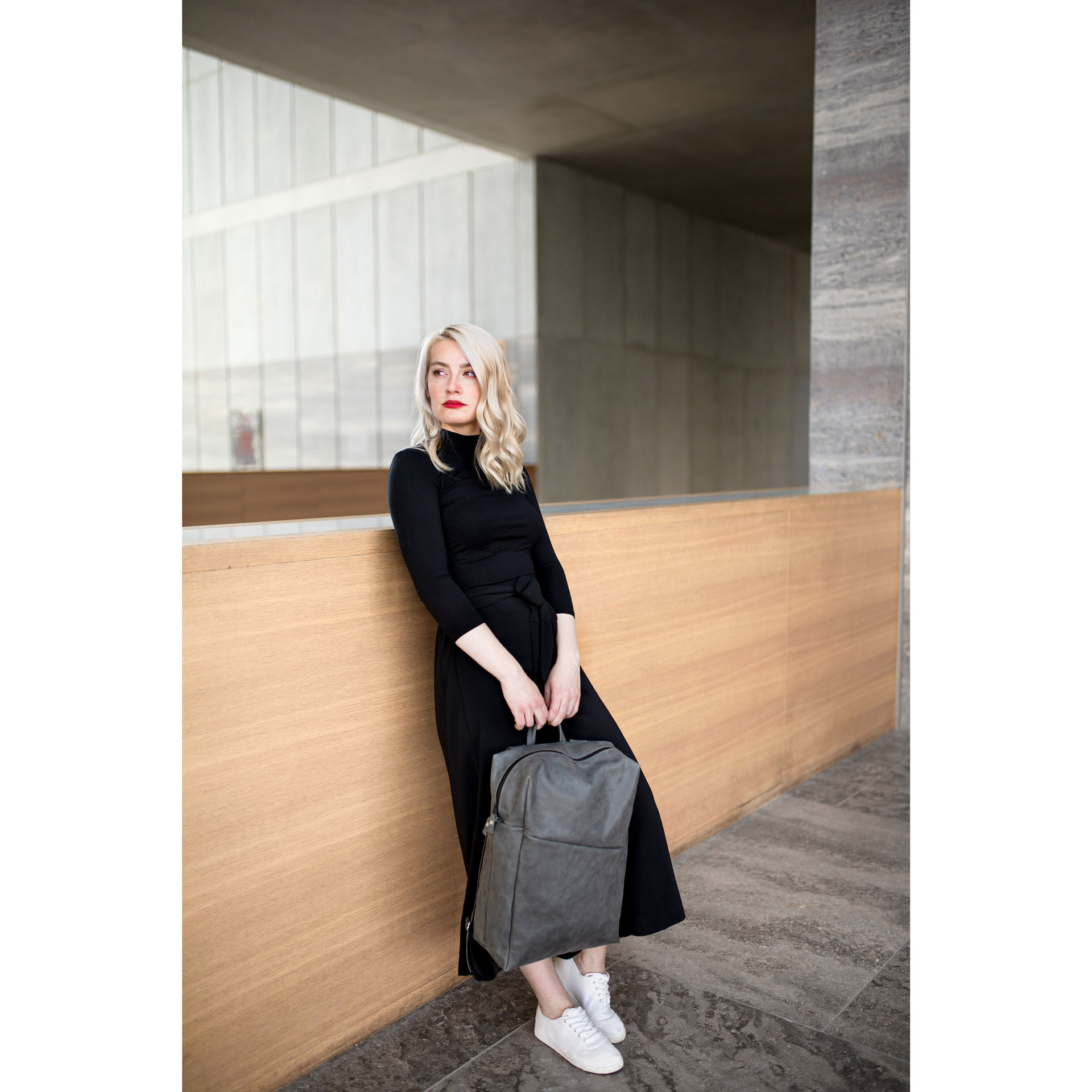 Model hält den Rucksack NEO Large in der Farbe Steingrau in den Händen.