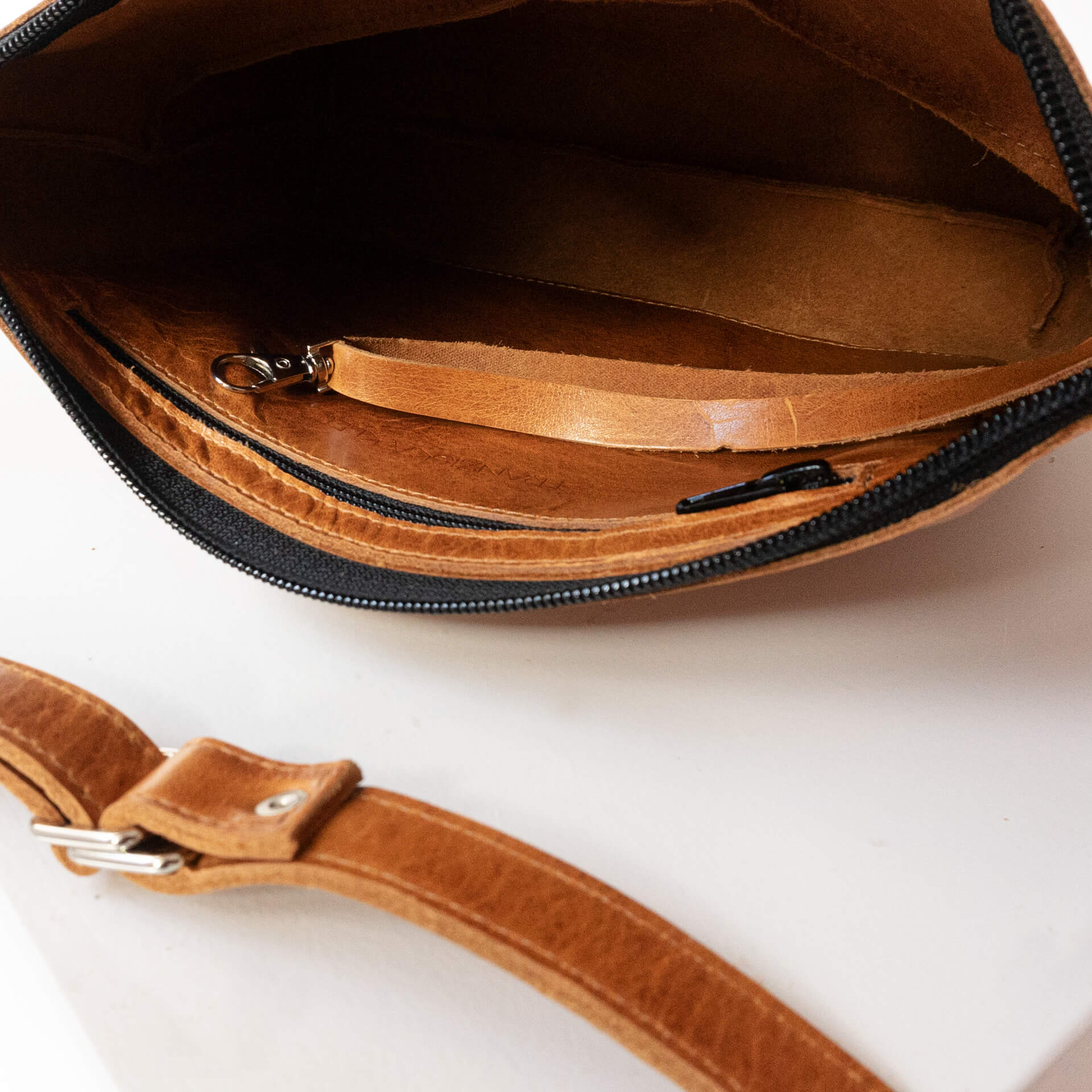 Detailansicht innen der Umhängetasche IDA mit Reißverschlussfach und Schlüsselkarabiner aus nachhaltigem Naturleder in Cognac geölt