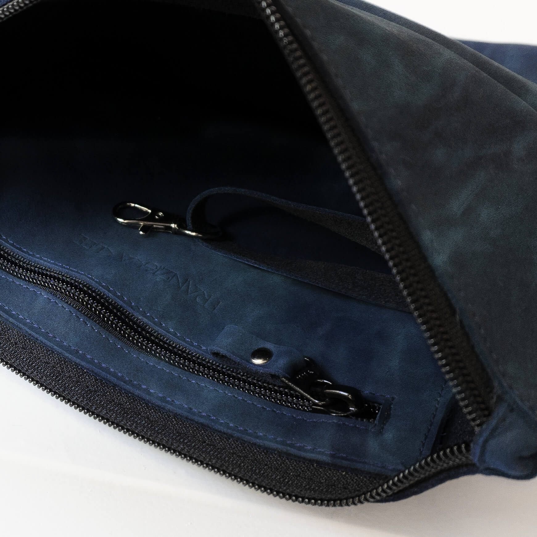 Detailansicht der Umhängetasche IDA aus Naturleder in Dunkelblau mit Reißverschlussfach und Schlüsselkarabiner