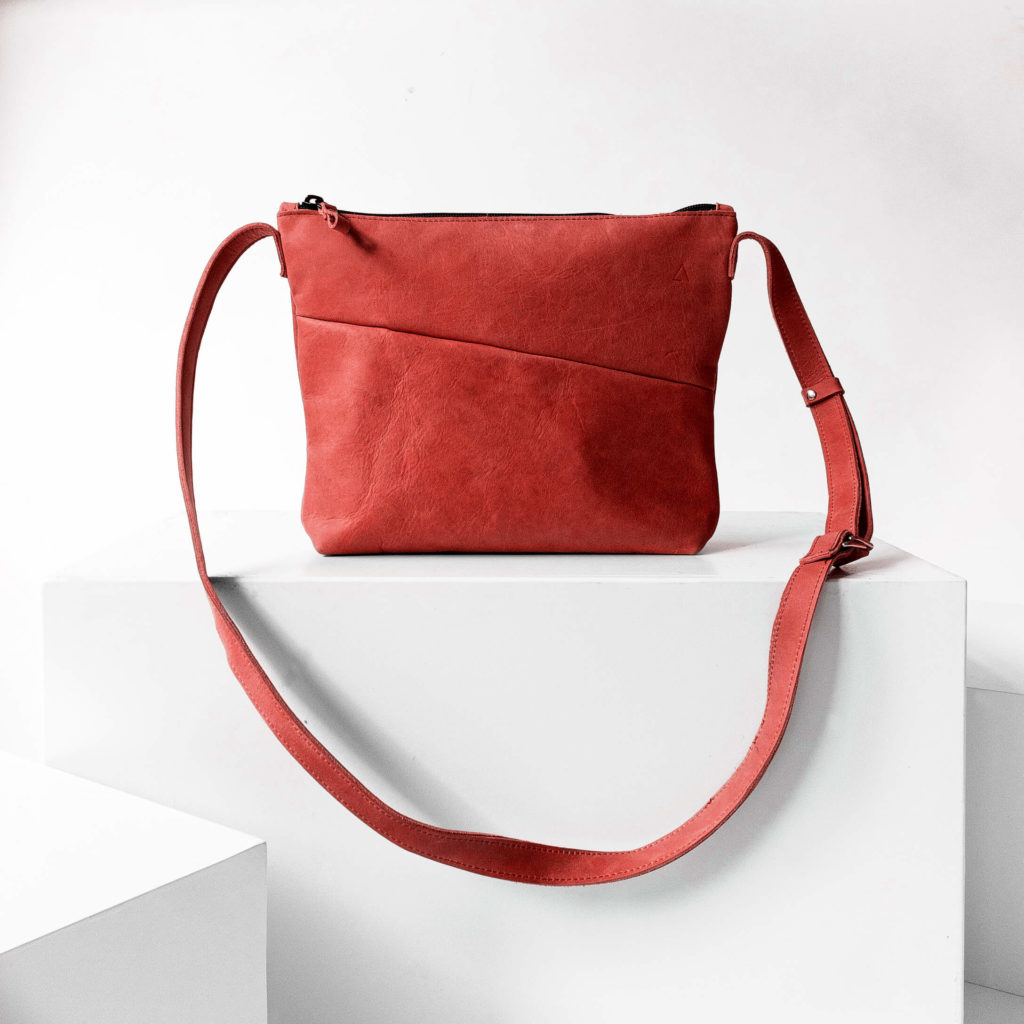 Vorderseite der Umhängetasche IDA aus nachhaltigem Naturleder in Rot auf Block stehend