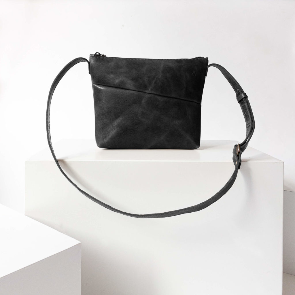 Vorderseite der Umhängetasche IDA aus nachhaltigem Naturleder in Schwarz geölt auf Block stehend