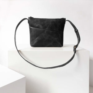 Vorderseite der Umhängetasche IDA aus nachhaltigem Naturleder in Schwarz geölt auf Block stehend