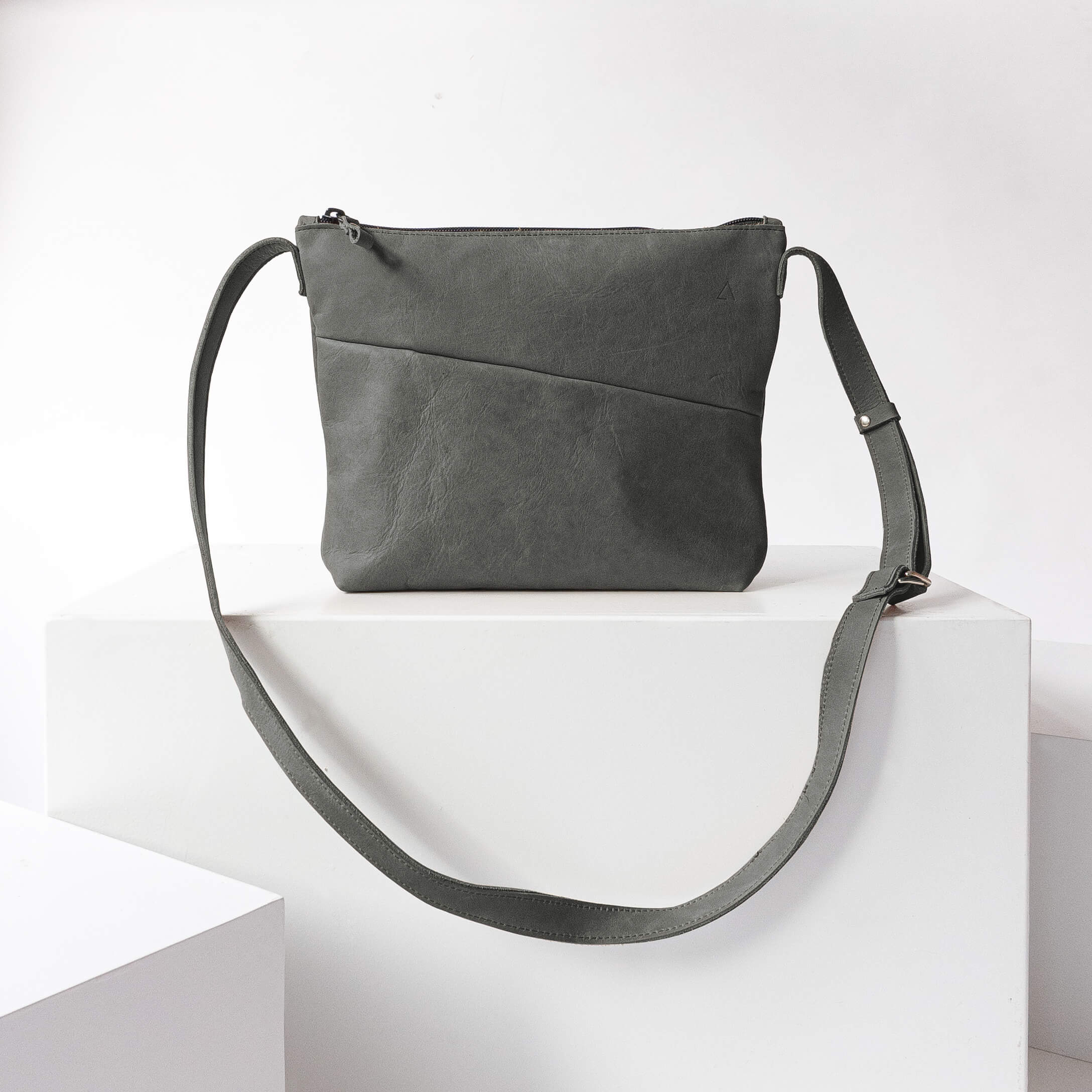 Umhängetasche IDA aus nachhaltigem Naturleder in Steingrau auf Block stehend von vorn