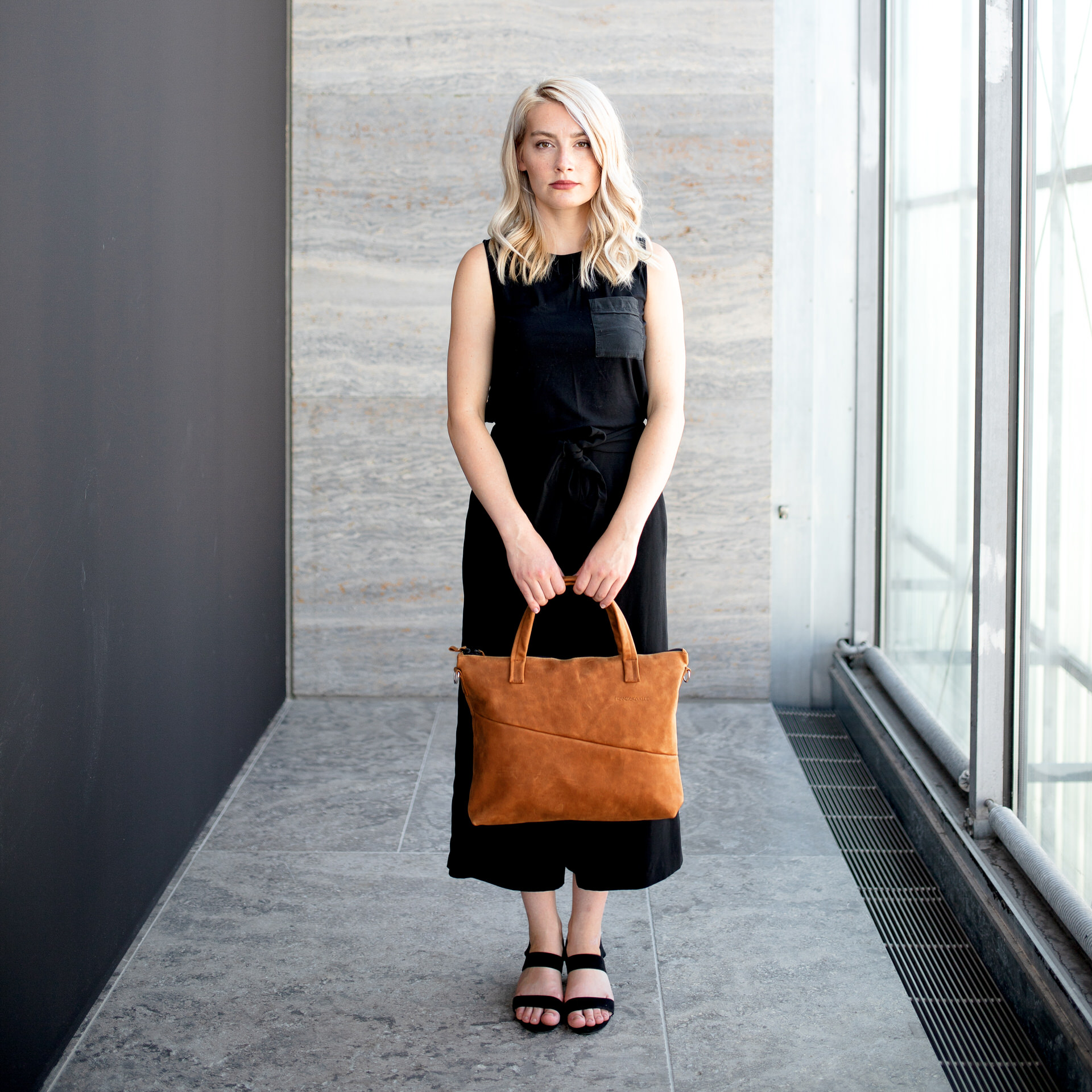 Model sitzt auf dem Boden und hält unsere Umhängetasche ANA in der Hand.