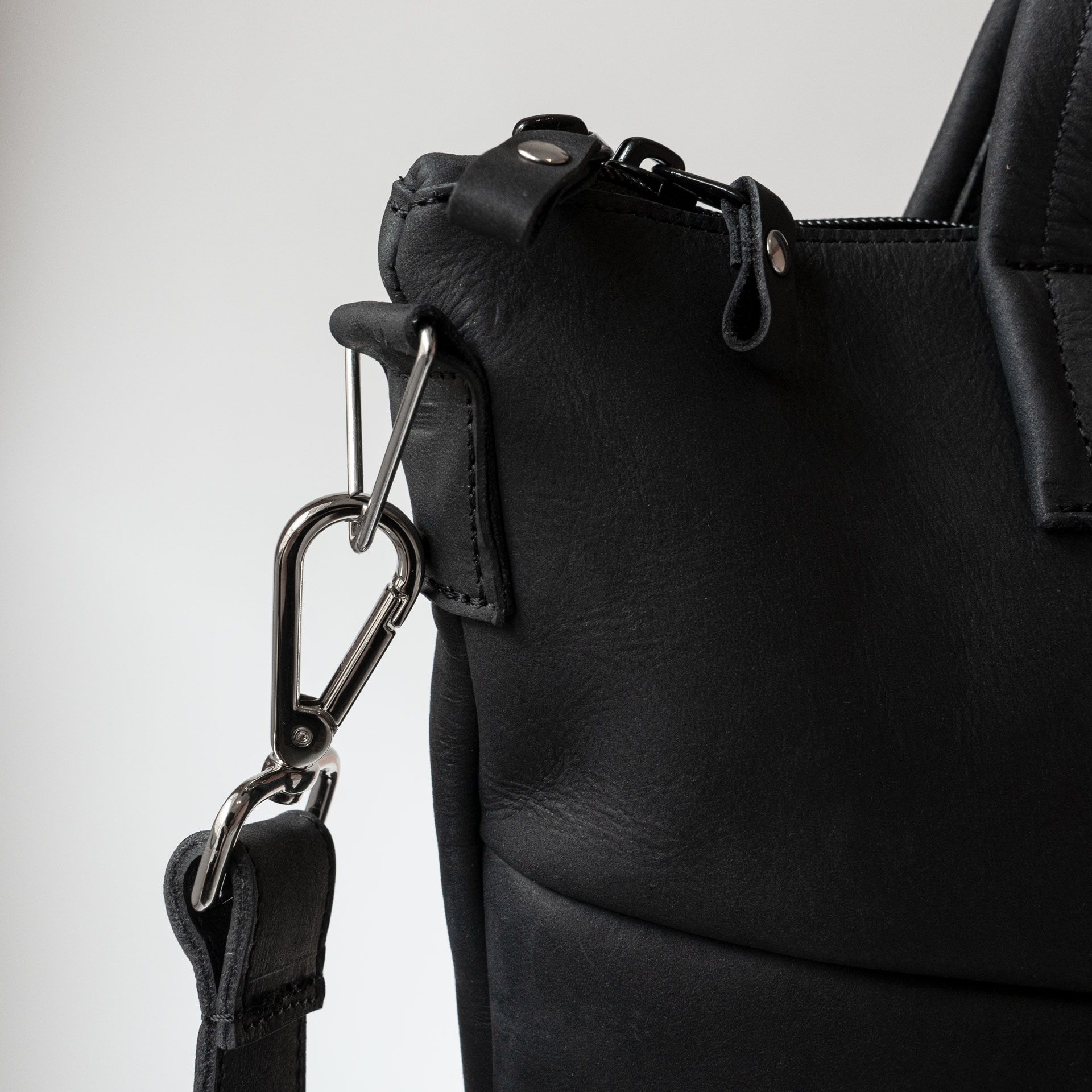 Detailaufnahme der Trägerhalterung mit Karabiner an Umhängetasche ANA aus Naturleder in Kohle