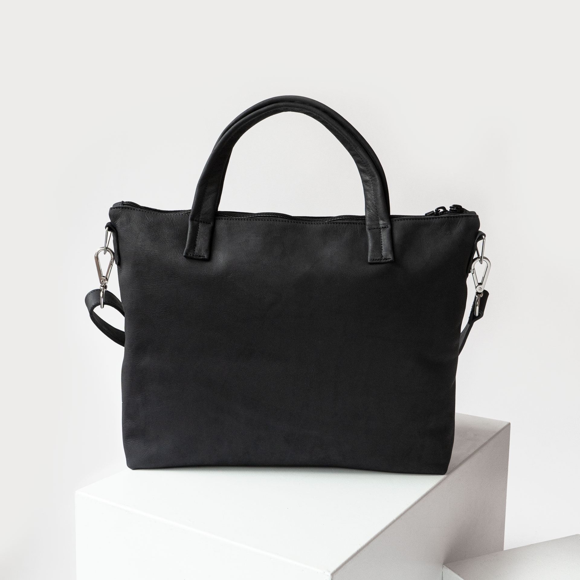 Rückansicht der Umhängetasche ANA aus Naturleder in Kohle mit Henkeln und abnehmbarem Träger