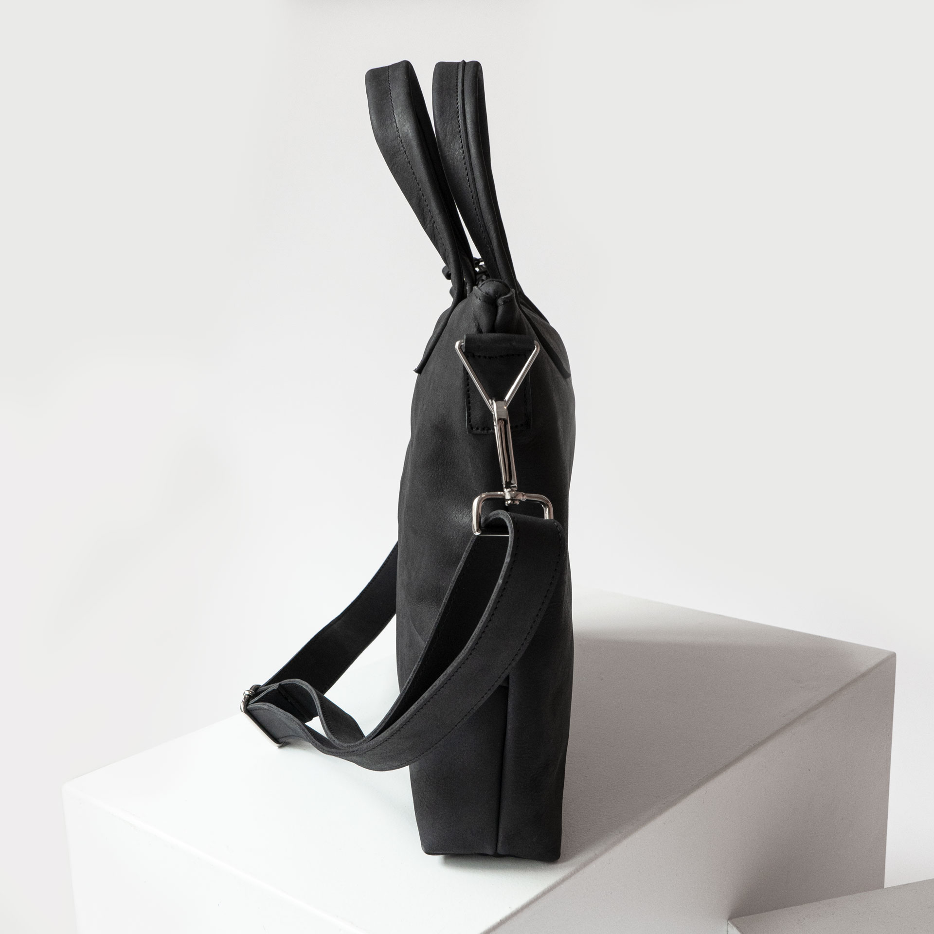 Seitenansicht Umhängetasche ANA mit Schultergurt und Henkeln aus kohlefarbenem Naturleder