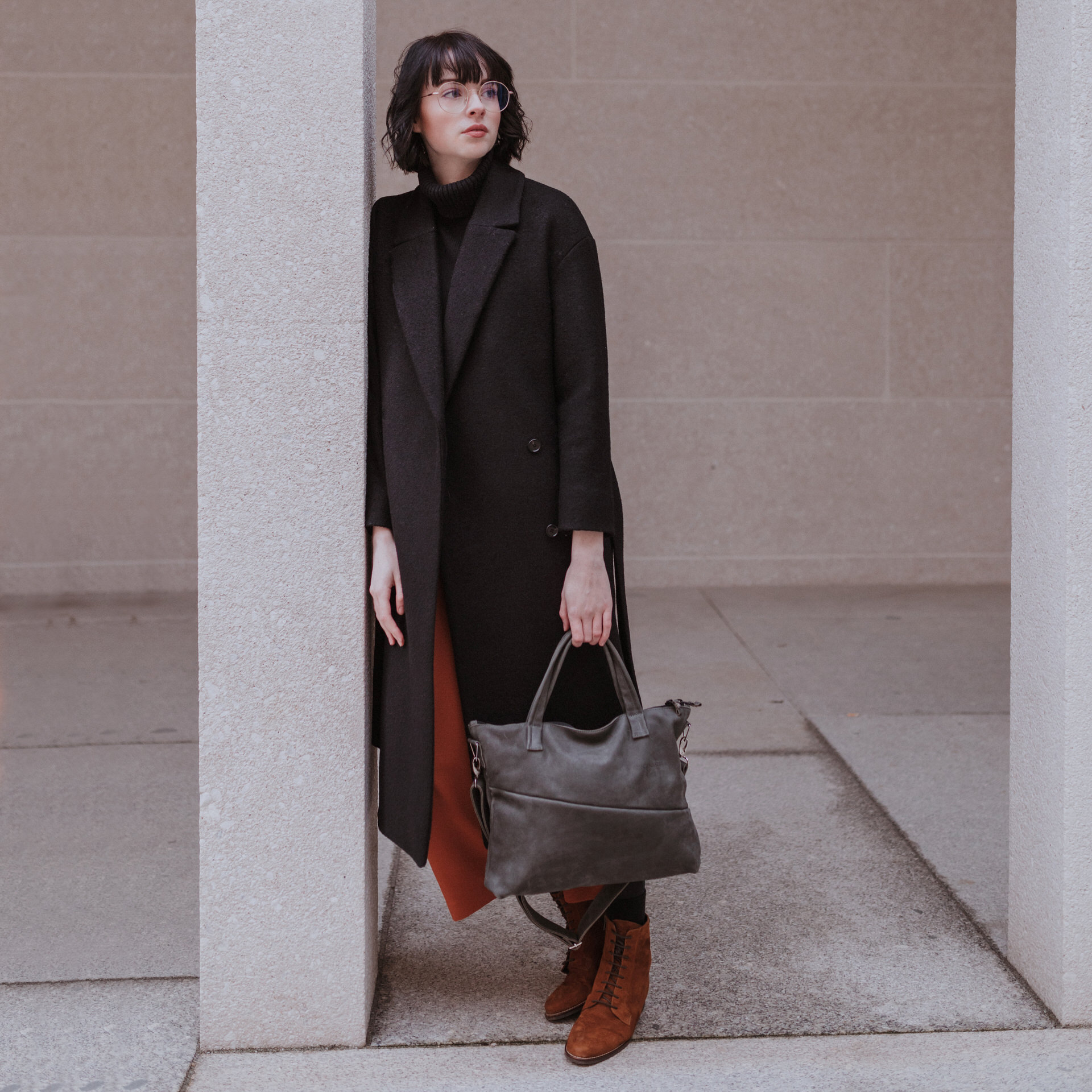 Model mit Handtasche ANA aus steingrauem Naturleder mit Henkeln und Schultergurt