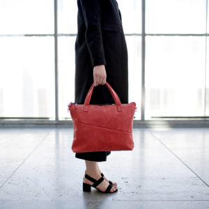 Model hält Umhängetasche ANA in der Farbe Rot in der Hand.