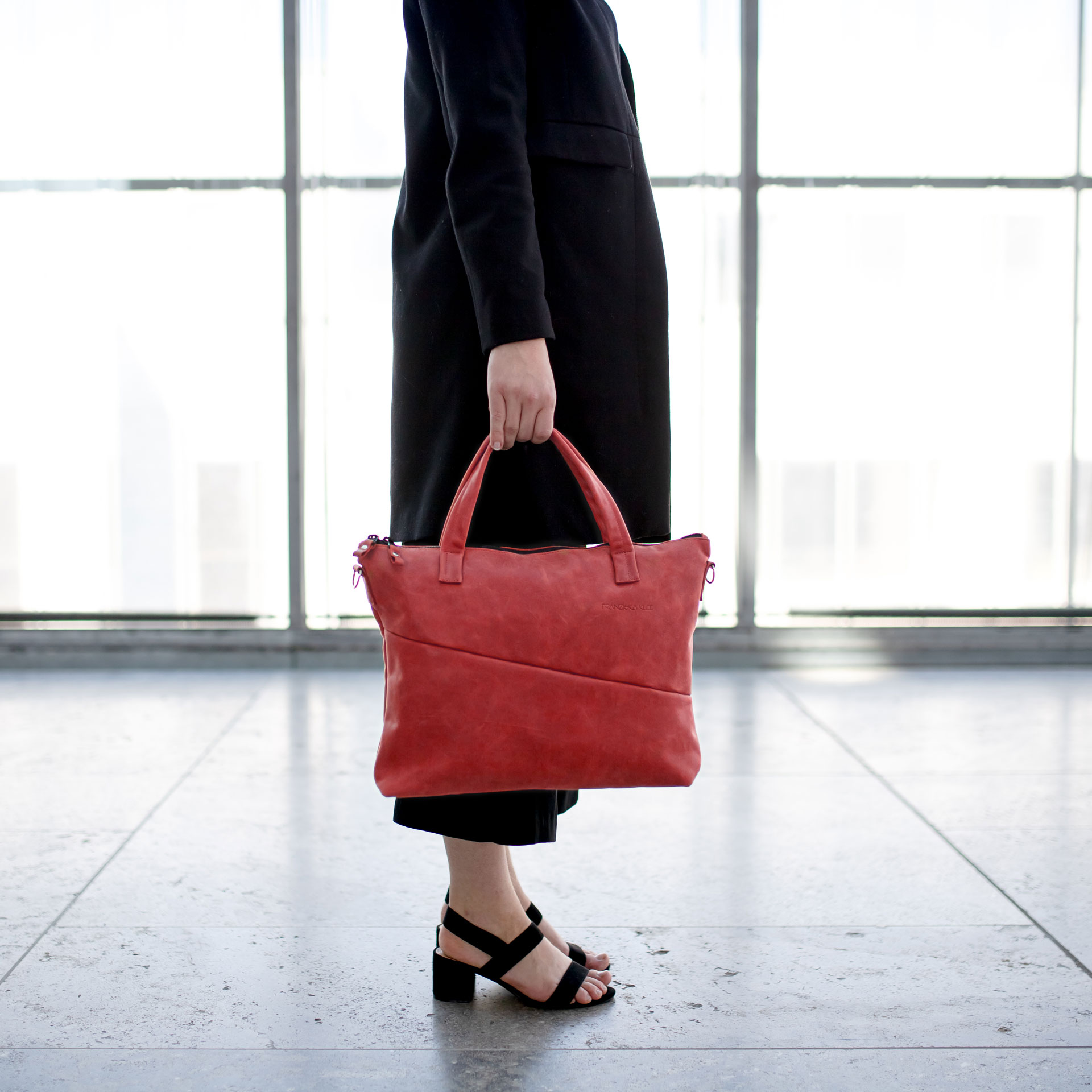 Model hält Umhängetasche ANA in der Farbe Rot in der Hand.