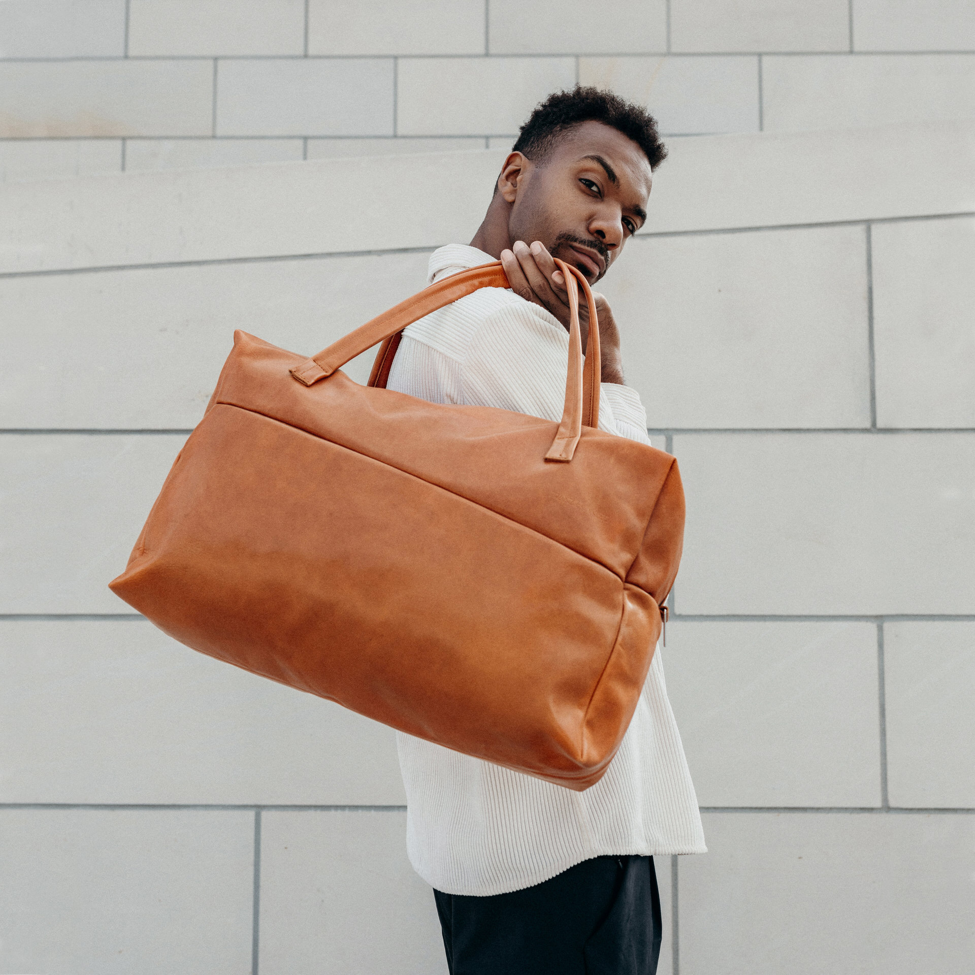 Model mit Weekender Reisetasche RIO mit Henkeln aus cognacfarbenem geölten Naturleder