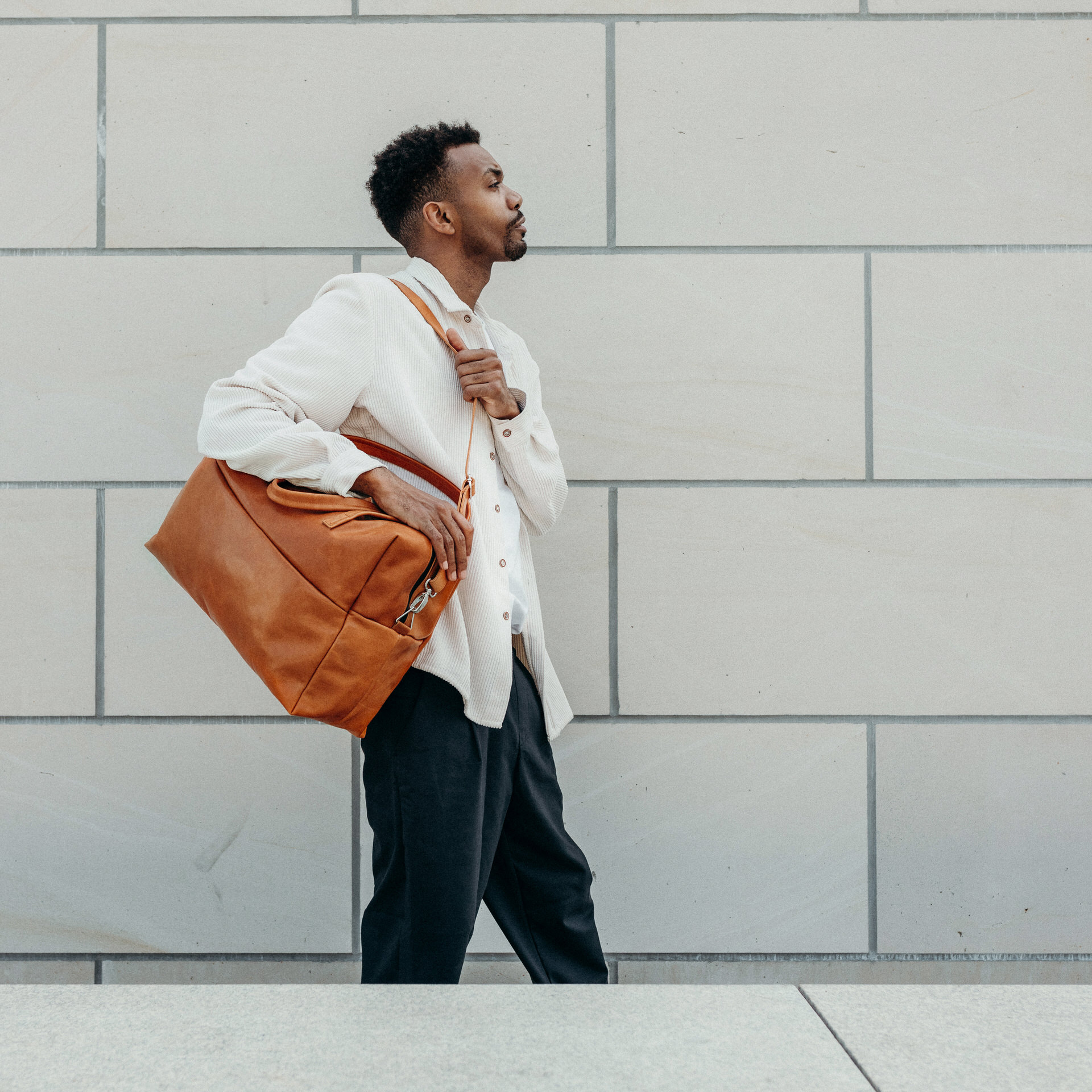 Model mit Weekender Reisetasche RIO mit Henkeln und Schultertasche aus cognacfarbenem geölten Naturleder