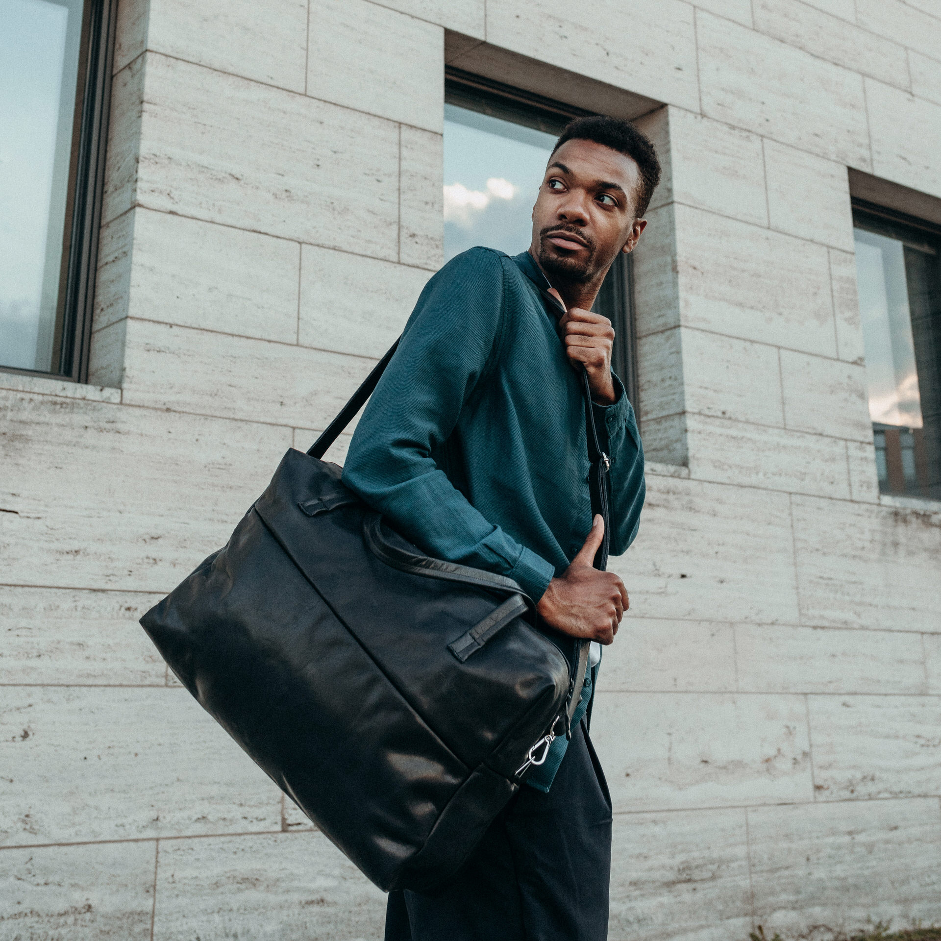 Model mit Weekender Reisetasche RIO mit Henkeln und Schultergurt aus schwarzem geölten Naturleder