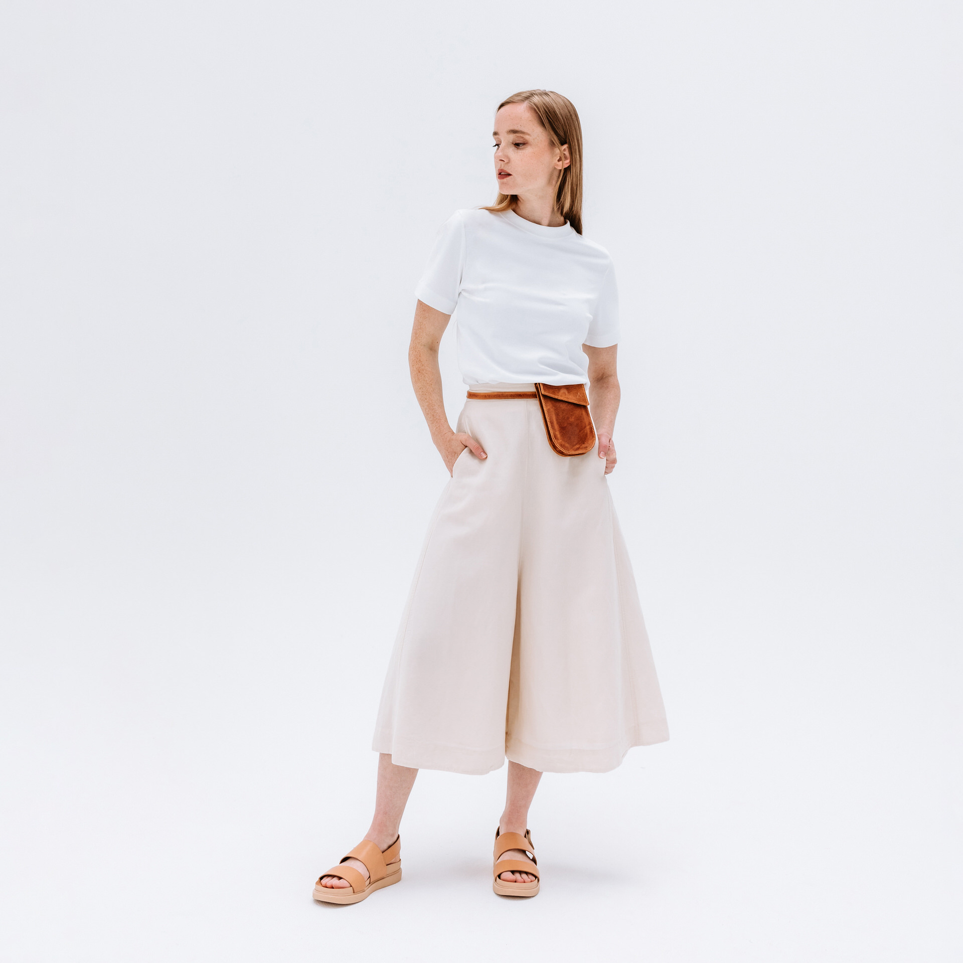 Model trägt Brustbeutel IRA in der Farbe Cognac geölt um die Hüfte.