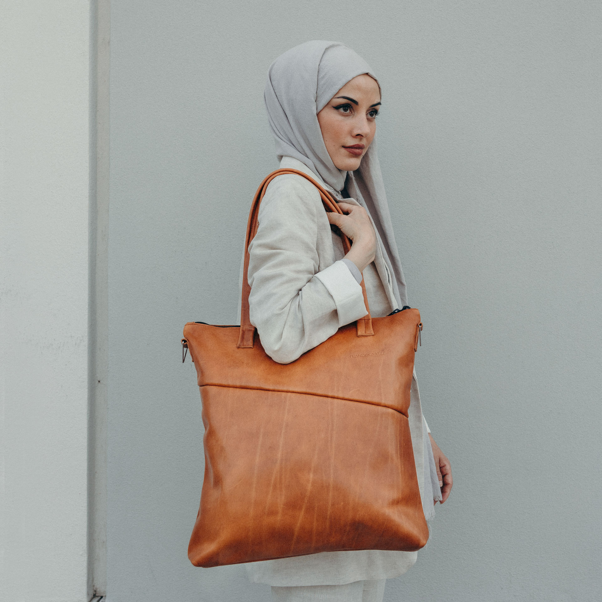Model trägt Shopper FIA in der Farbe Cognac geölt über der Schulter.