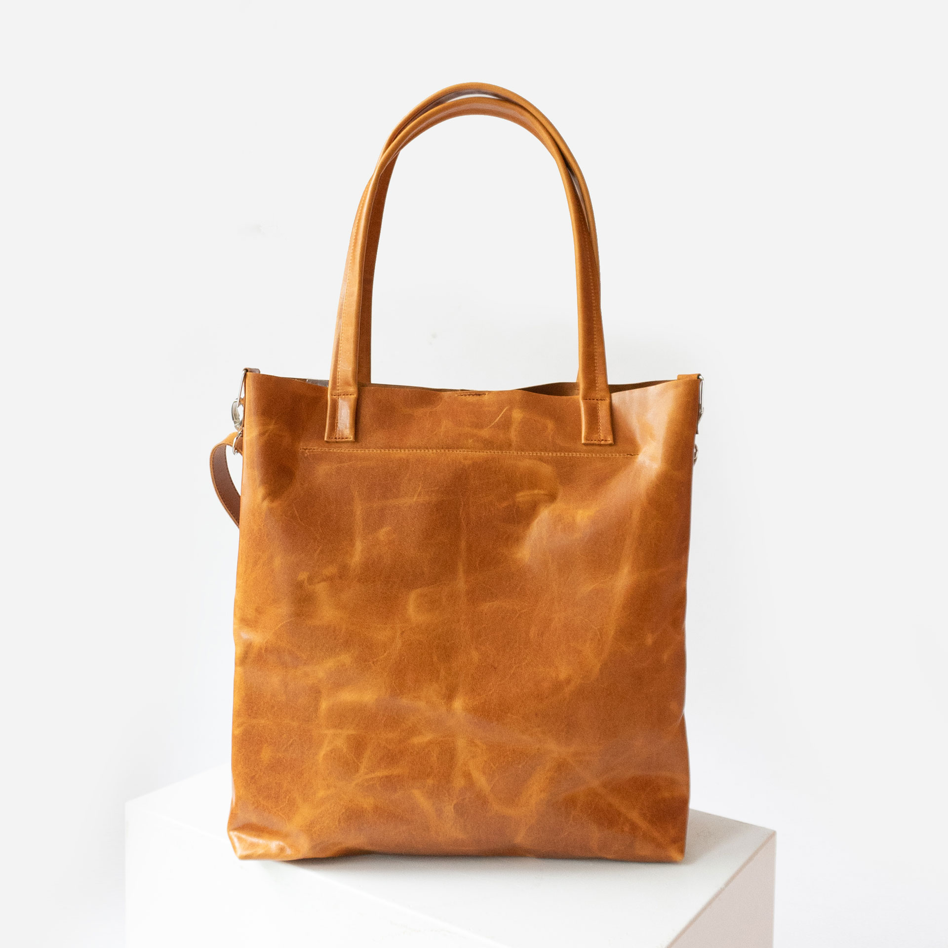 Rückseite der Wickeltasche MIA MIDI aus nachhaltigem Naturleder in Cognac geölt mit langen Henkeln und abnehmbarem Umhängegurt