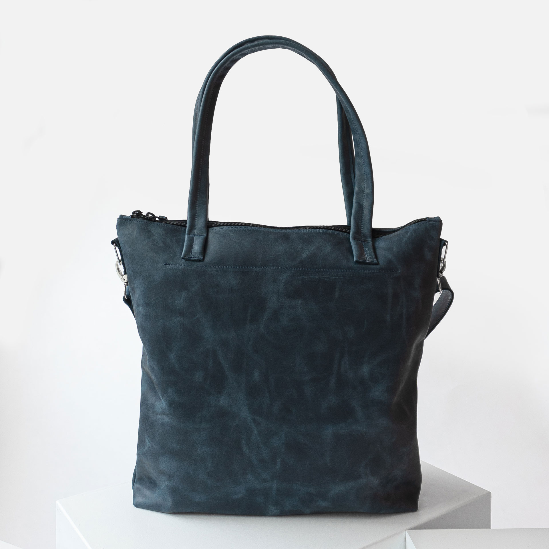 Rückseite der Wickeltasche MIA MIDI aus nachhaltigem Naturleder in Dunkelblau mit langen Henkeln und abnehmbarem Umhängegurt