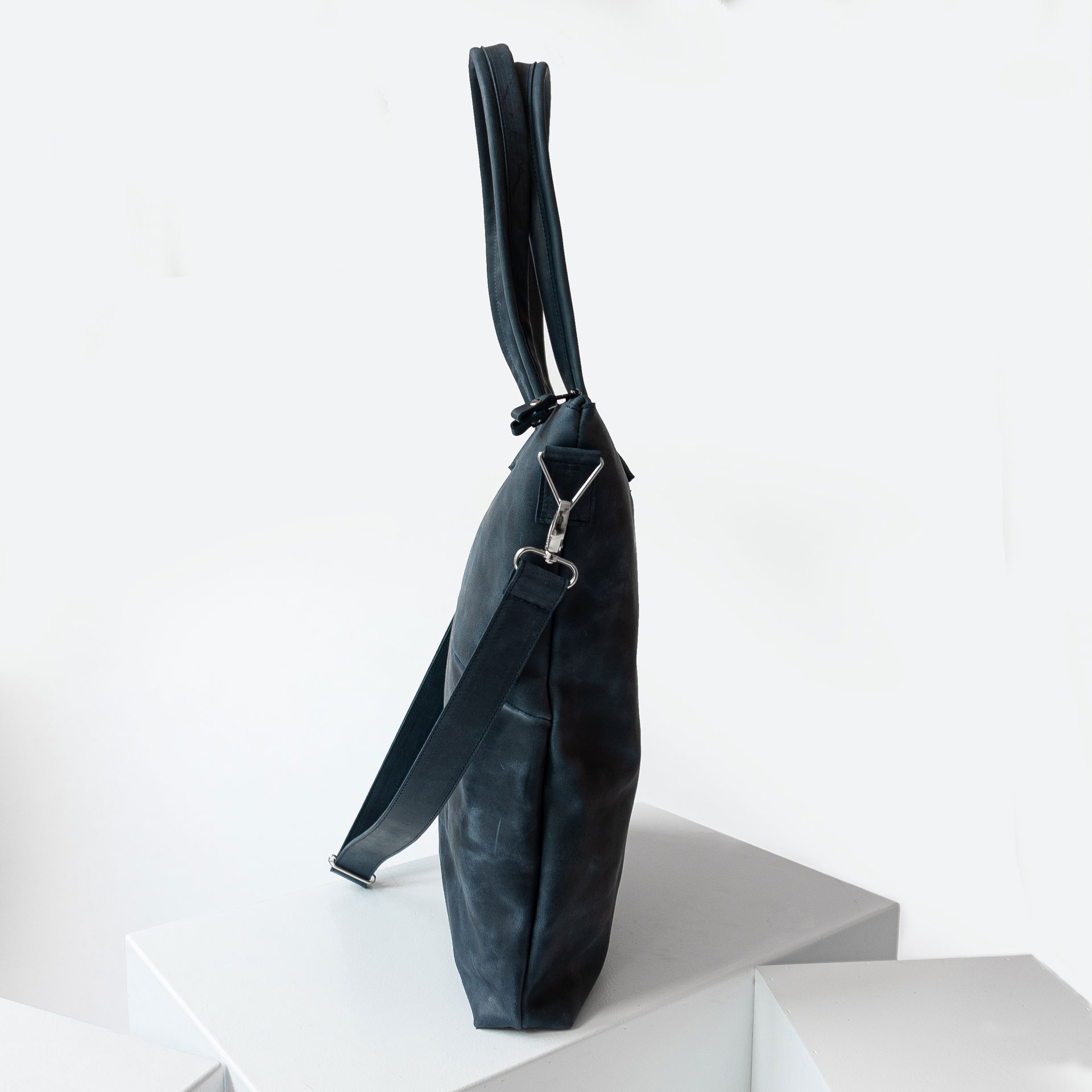 Seitenansicht der Wickeltasche MIA MIDI aus nachhaltigem Naturleder in Dunkelblau mit abnehmbarem Umhängegurt