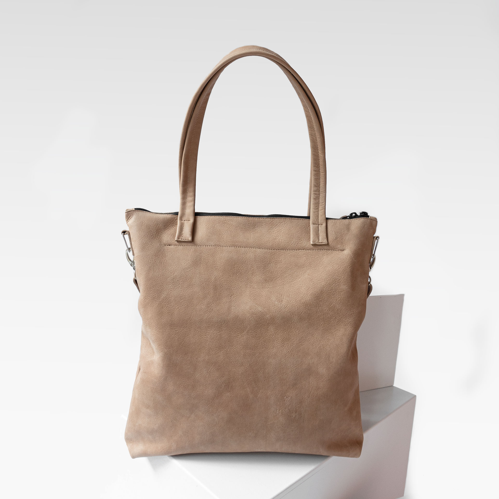 Rückseite der Wickeltasche MIA MIDI aus nachhaltigem Naturleder in Hellbraun mit langen Henkeln und abnehmbarem Umhängegurt