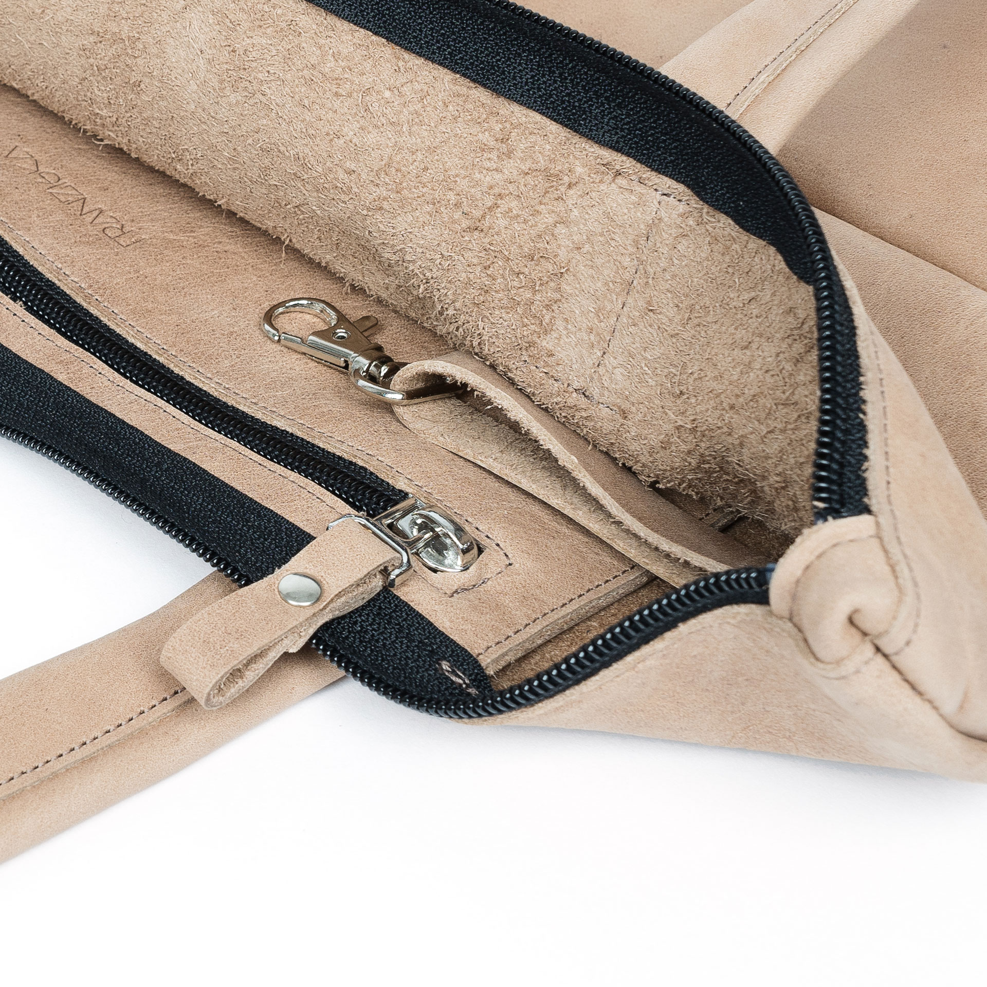 Detailansicht innen der Wickeltasche MIA MIDI aus Naturleder in Hellbraun mit Reißverschlussinnenfach, Schlüsselkarabiner und dezenter Logoprägung