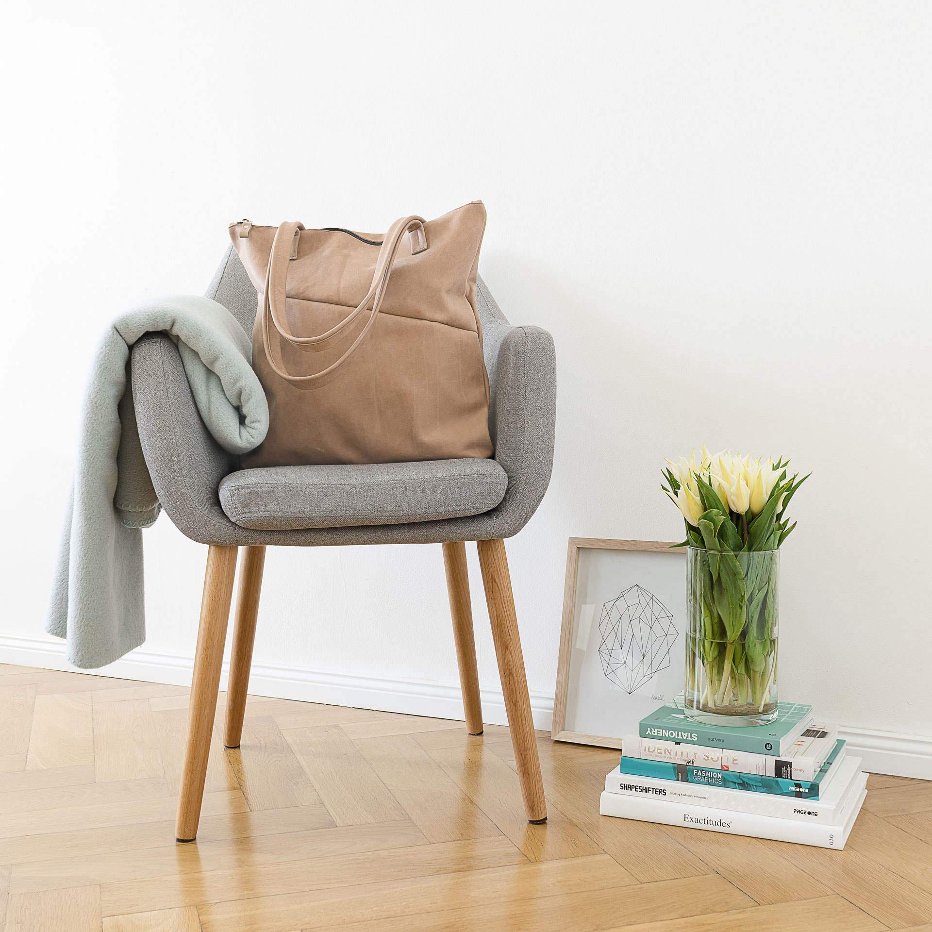 Moodshot Wickeltasche MIA MIDI aus nachhaltigem Naturleder in Steingrau auf einem Stuhl stehend