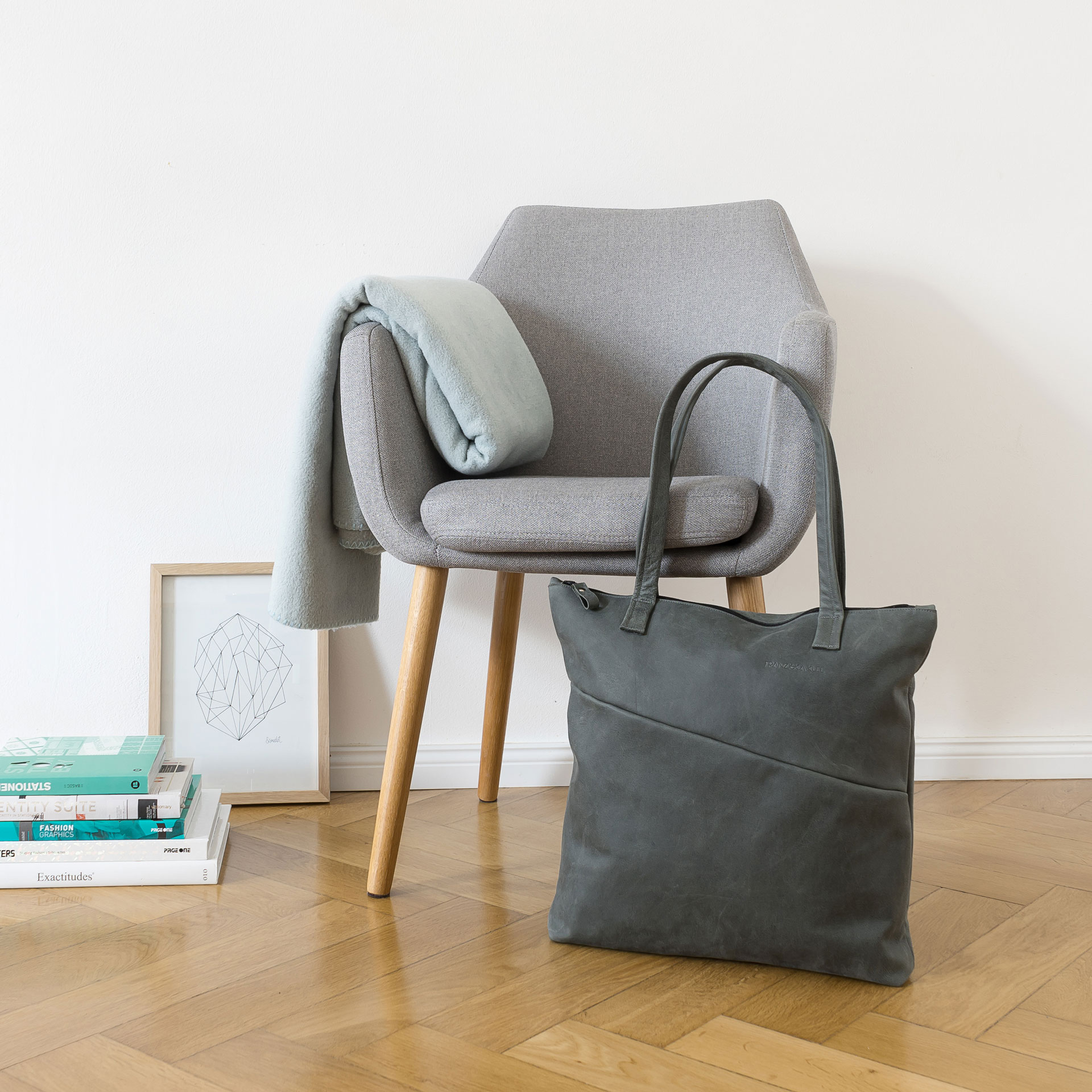 Moodshot Wickeltasche MIA MIDI aus nachhaltigem Naturleder in Steingrau vor Stuhl