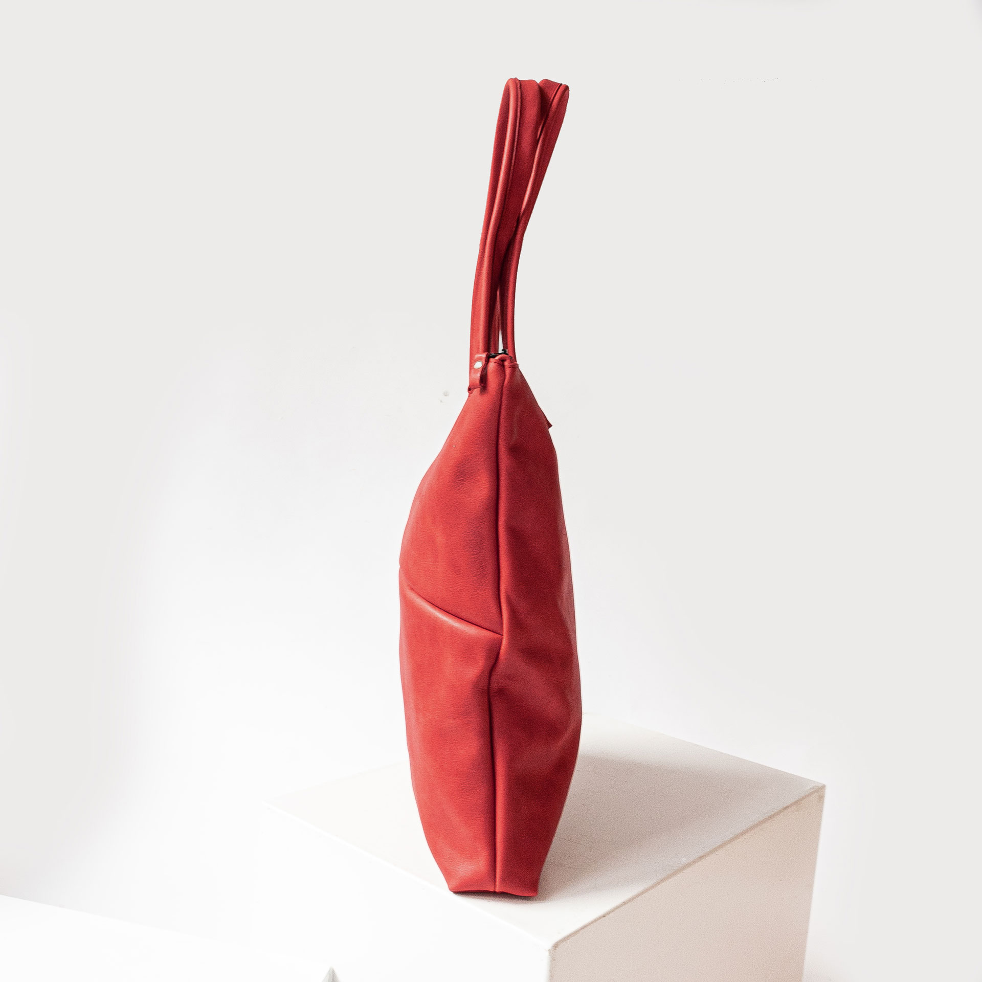 Seitenansicht der Wickeltasche MIA MIDI aus nachhaltigem Naturleder in Rot