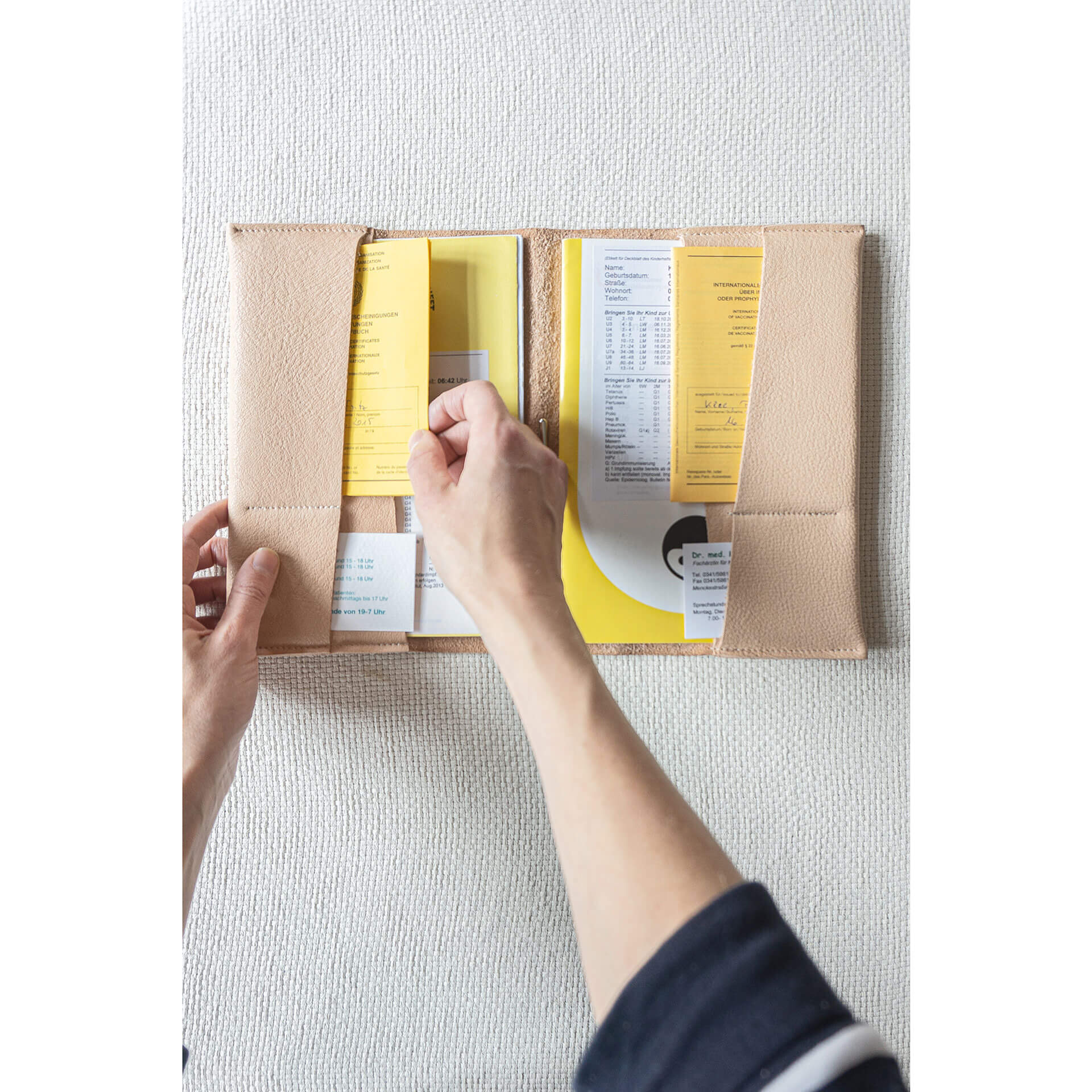 Mood Shot U-Hefthülle EVE als Geschwisterhülle aus nachhaltigem Naturleder in Beige auf geklappt mit U-Heften, Impfpässen und Visitenkarten