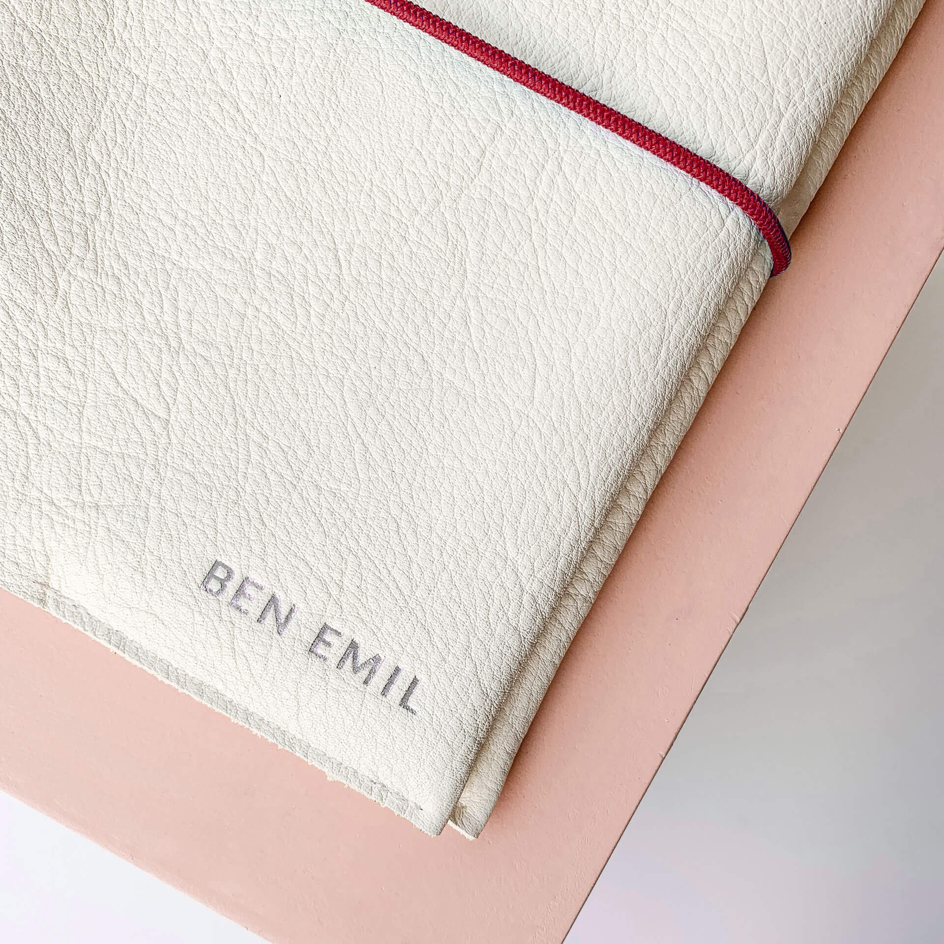 Detailaufnahme Silberfarbene Namensprägung auf U-Hefthülle EVE in Creme mit rotem Verschlussband