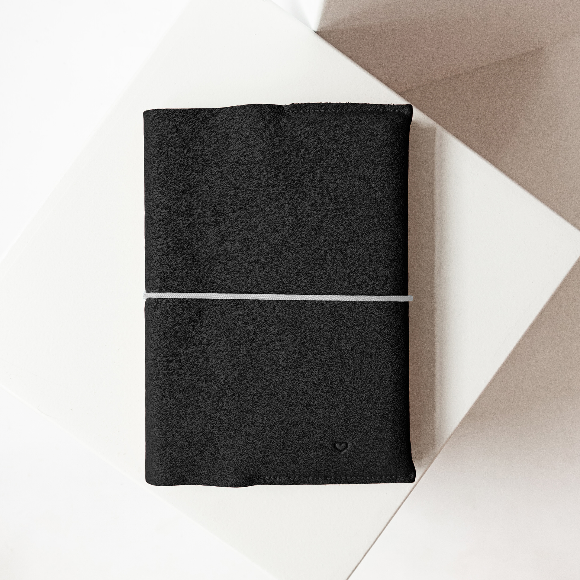 U-Hefthülle EVE aus nachhaltigem Naturleder in Schwarz mit schlichter Herz-Prägung und grauem Verschlussband