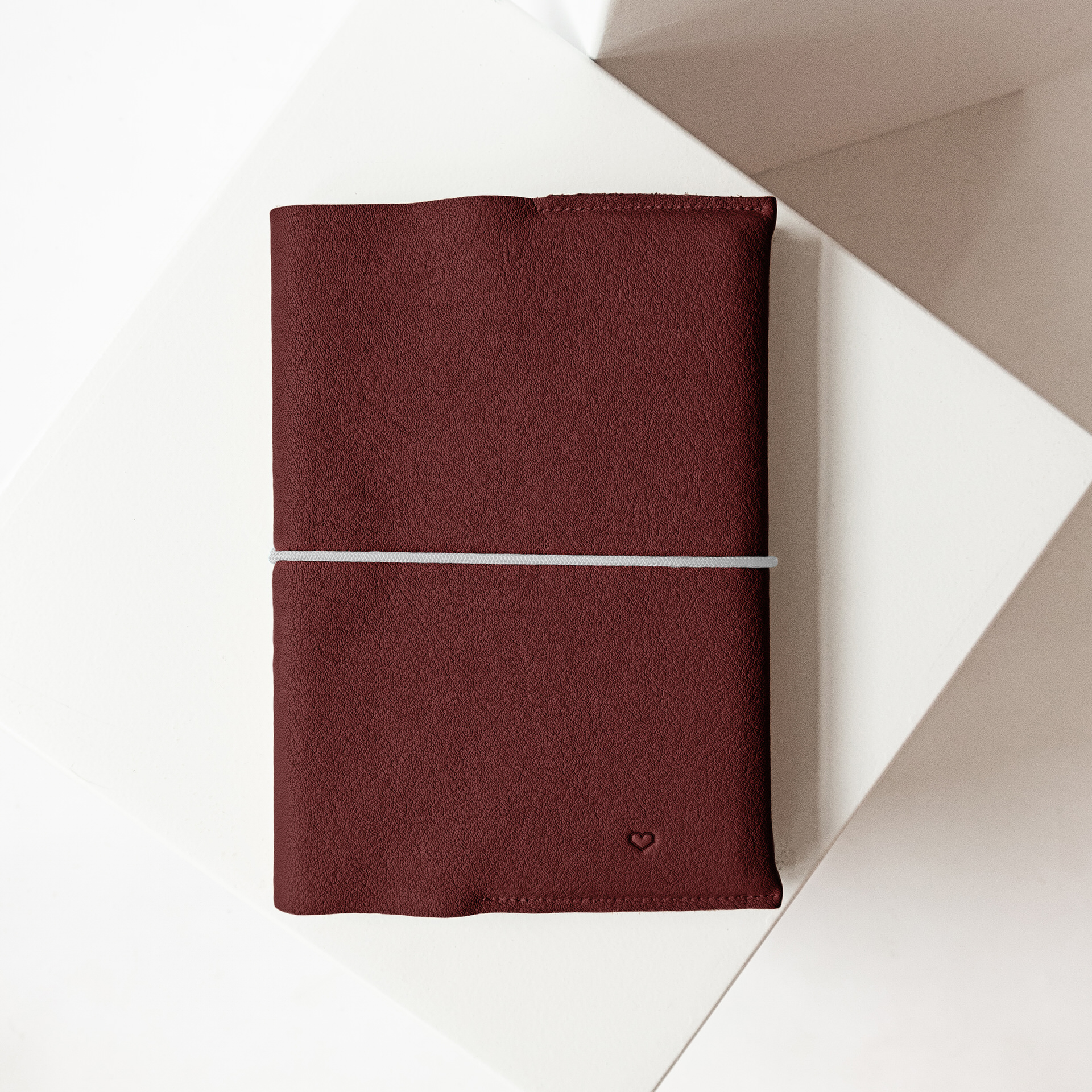 U-Hefthülle EVE aus nachhaltigem Naturleder in Weinrot mit schlichter Herz-Prägung und grauem Verschlussband
