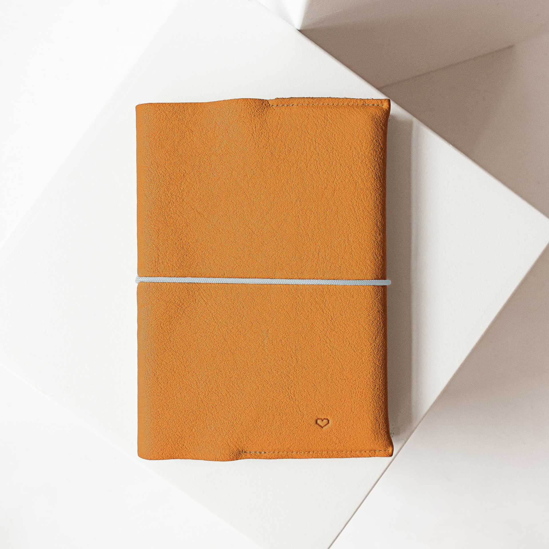U-Hefthülle EVE aus nachhaltigem Naturleder in Cognac mit schlichter Herz-Prägung und blauem Verschlussband